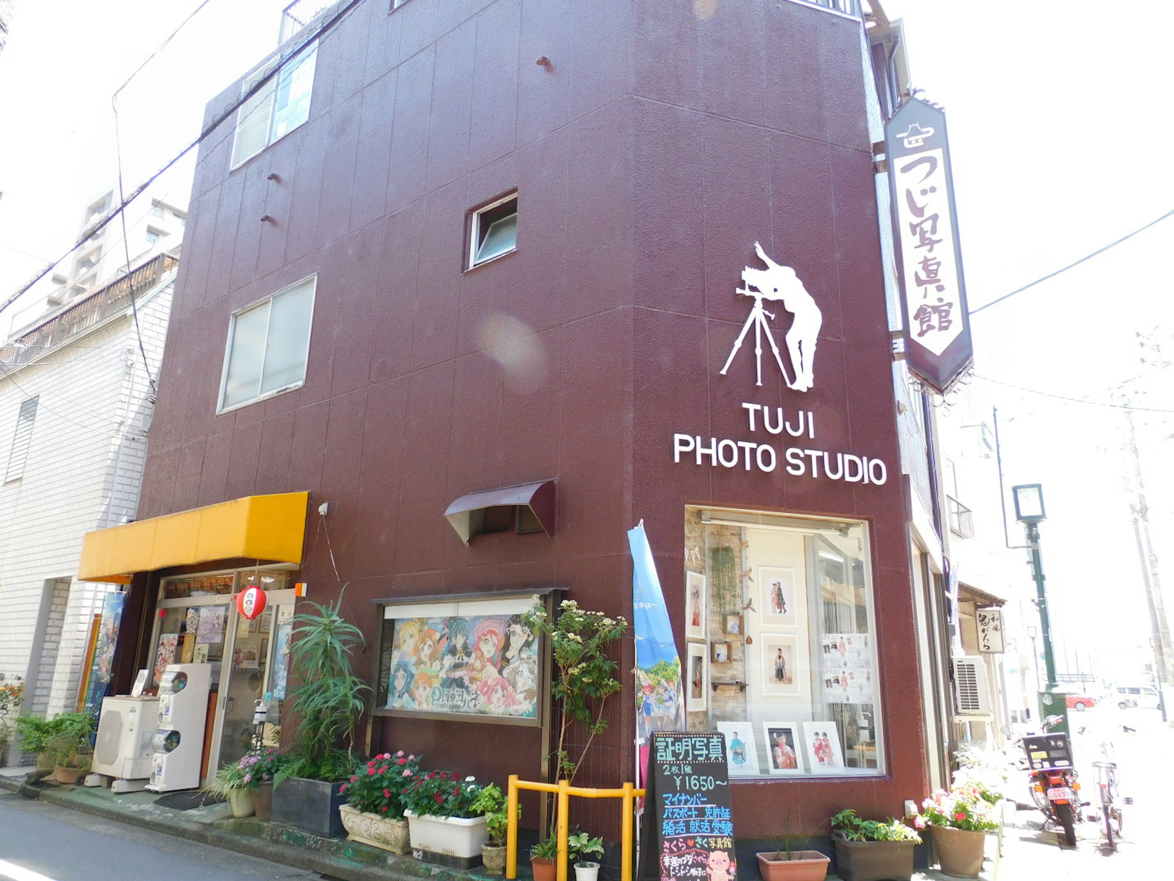 อาคารภายนอกสีน้ำตาลของ Tuji Photo Studio บนถนน