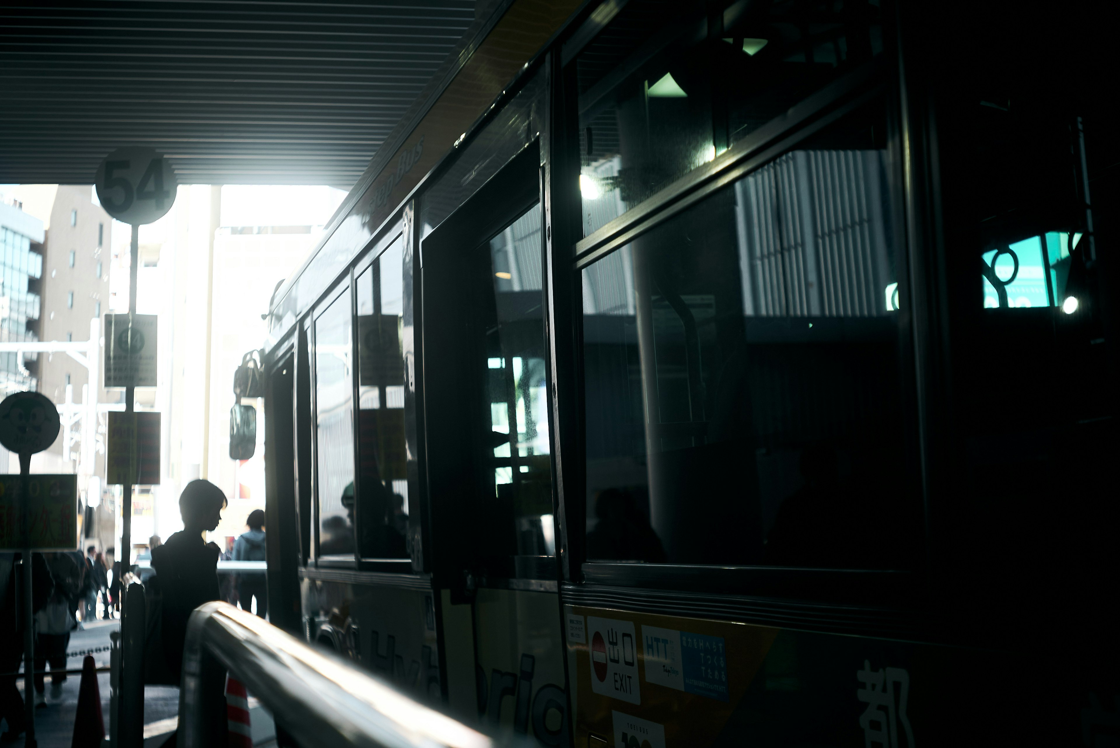 Siluet bus dan penumpang di halte dengan cahaya sekitar