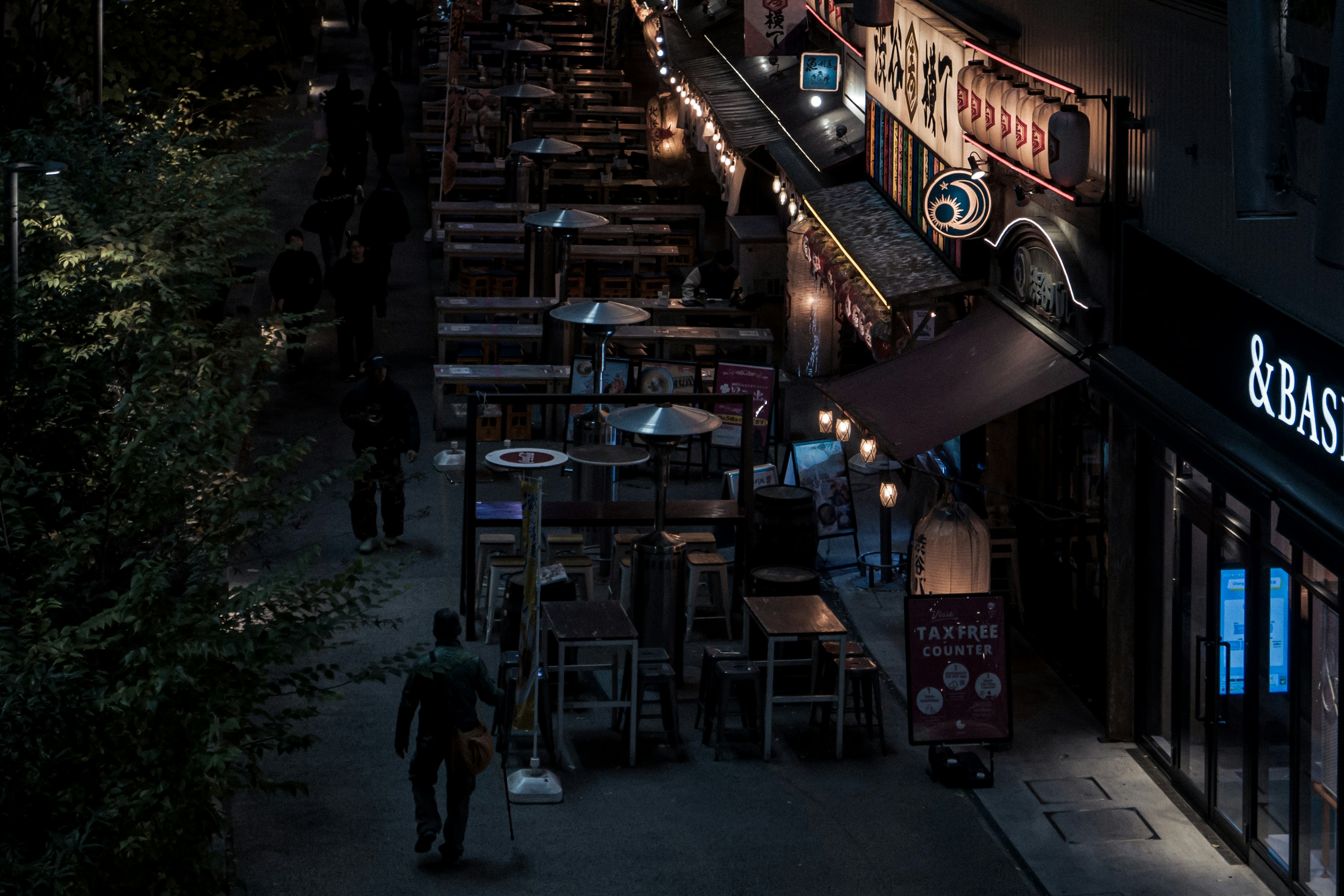 Escena nocturna de la calle con mesas de comedor al aire libre y restaurantes