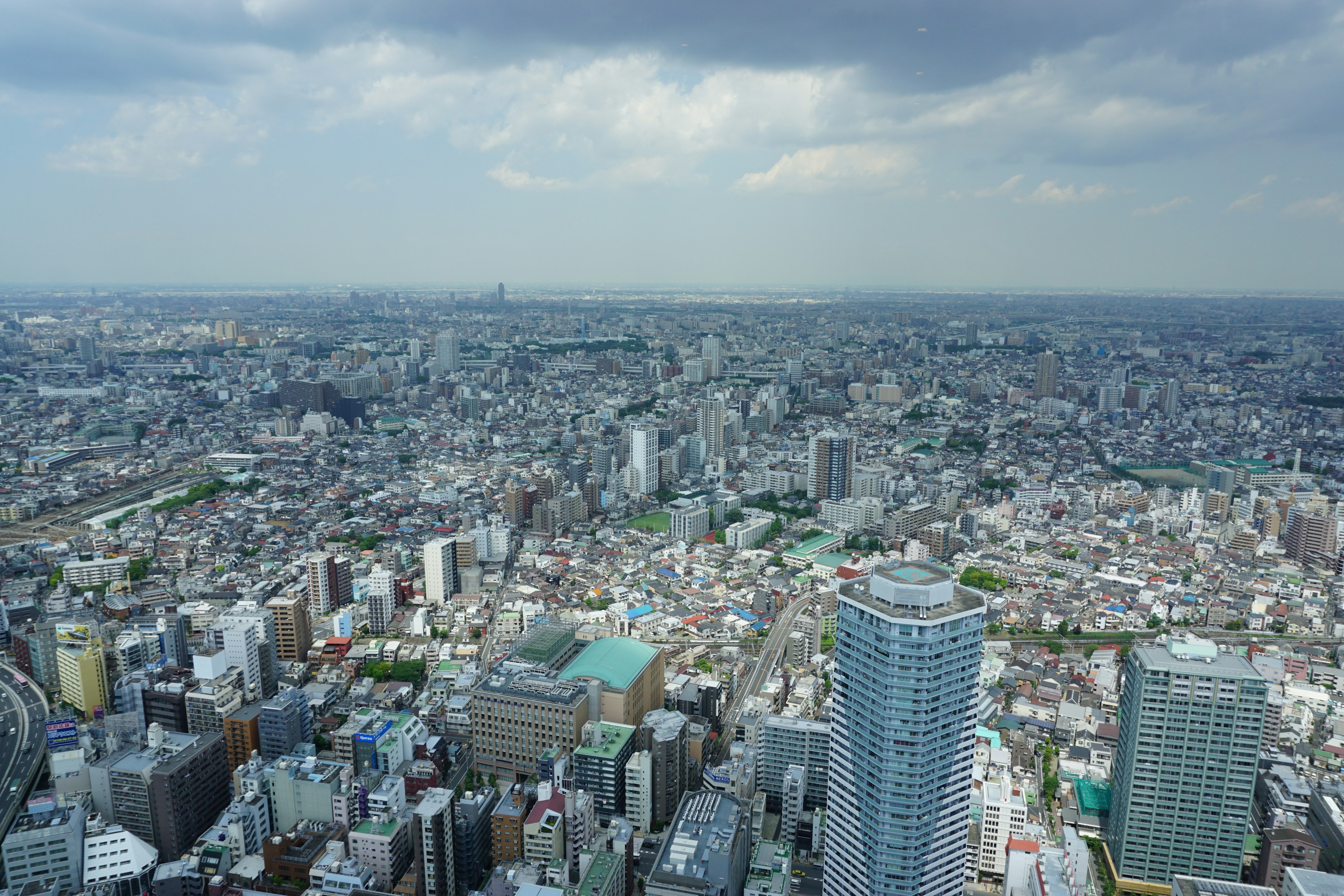 Cảnh quan đô thị rộng lớn của Tokyo với các tòa nhà chọc trời và bầu trời nhiều mây