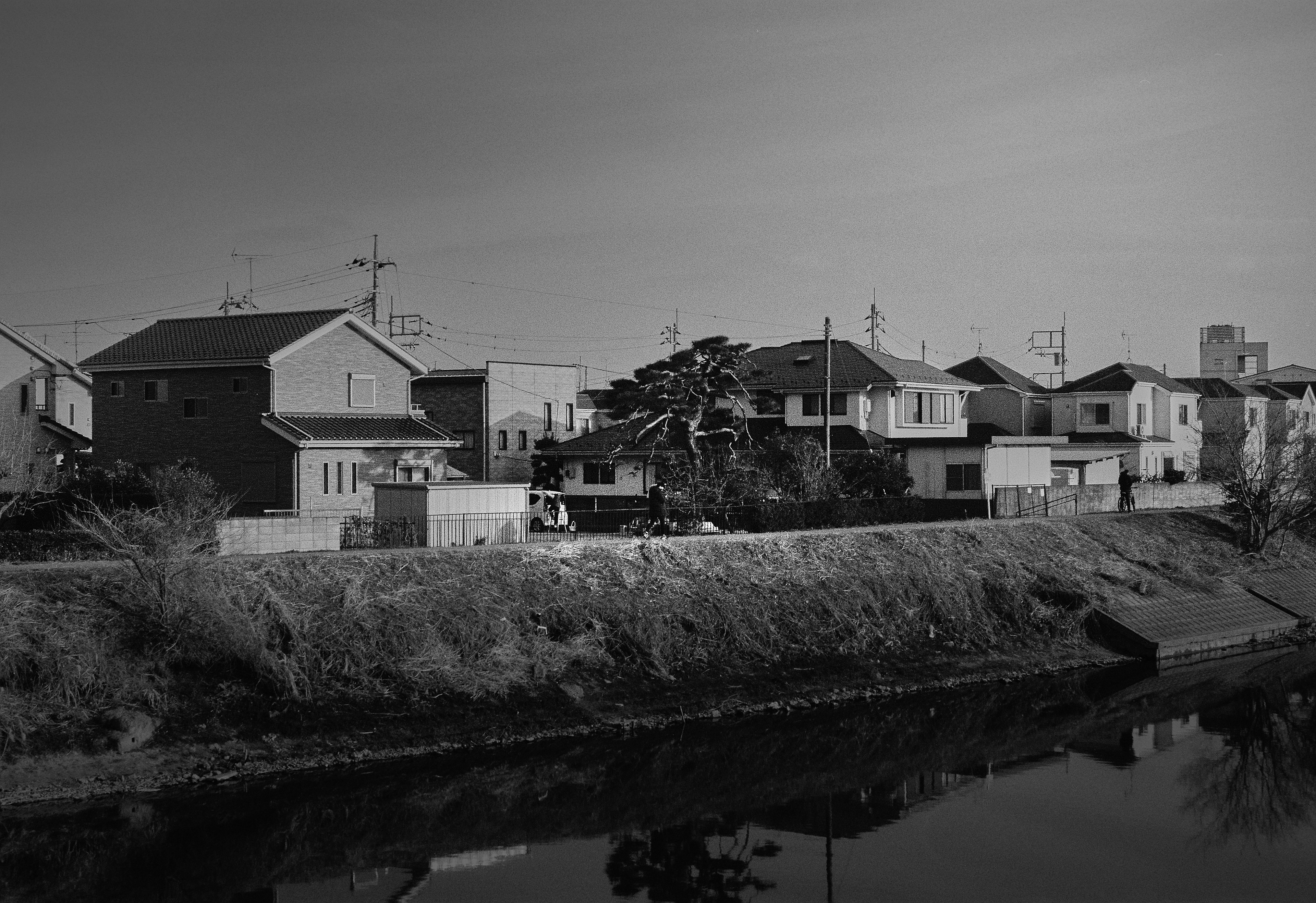 モノクロの川沿いに建つ住宅街の景観