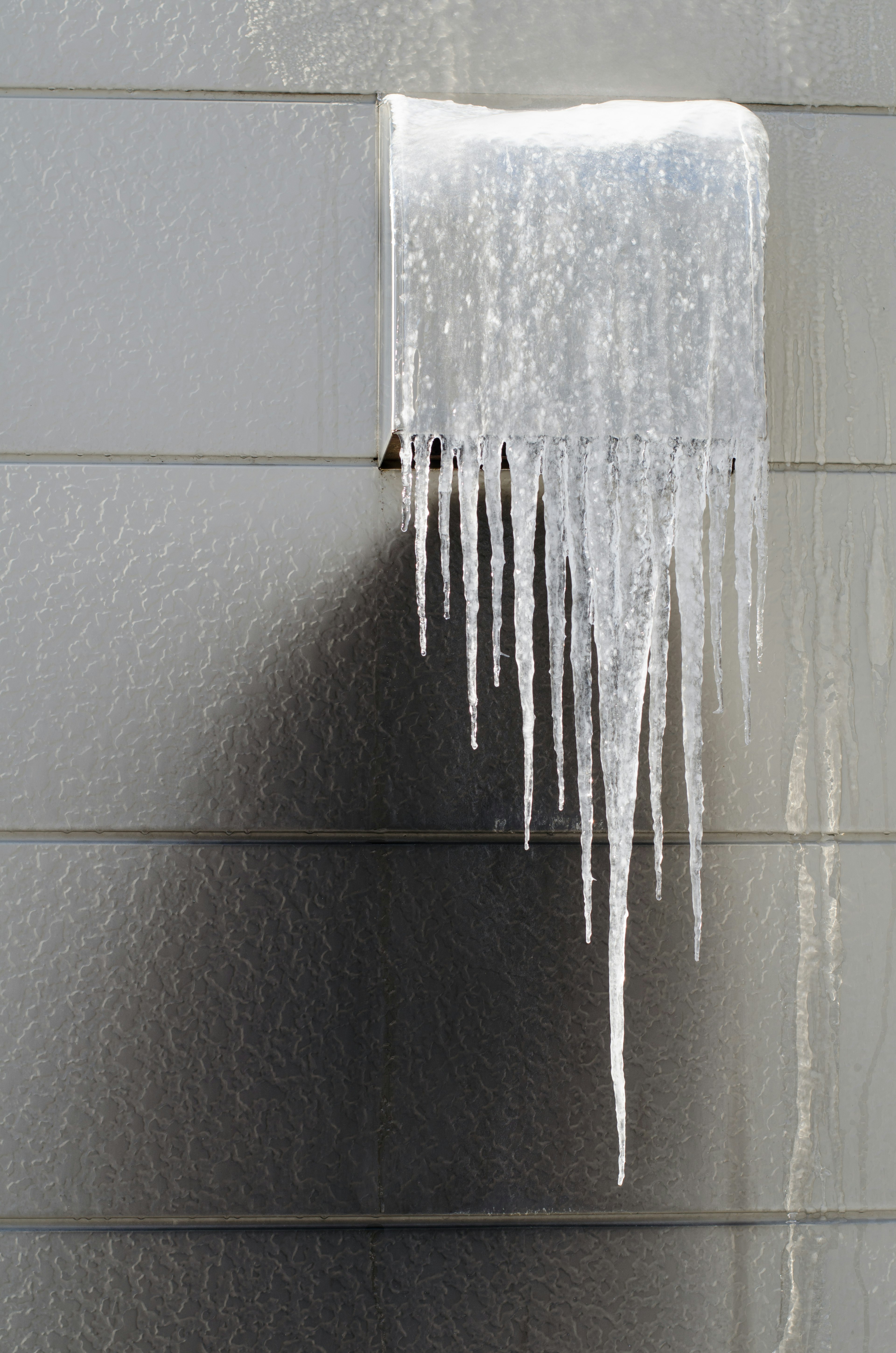 Eiszapfen hängen von einer Wand und schaffen eine kalte Winterszene