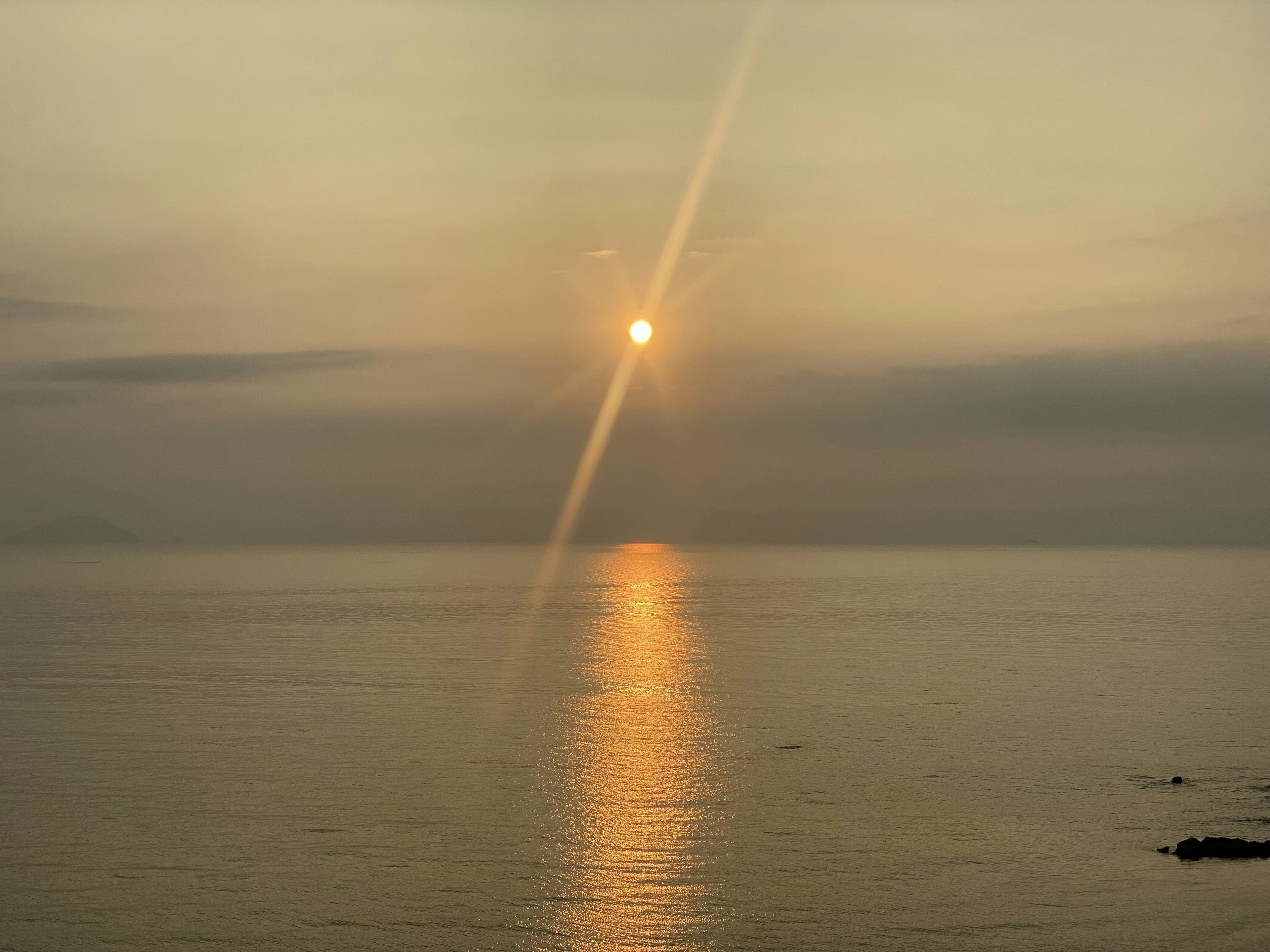 穏やかな海の上に沈む夕日とその光の反射