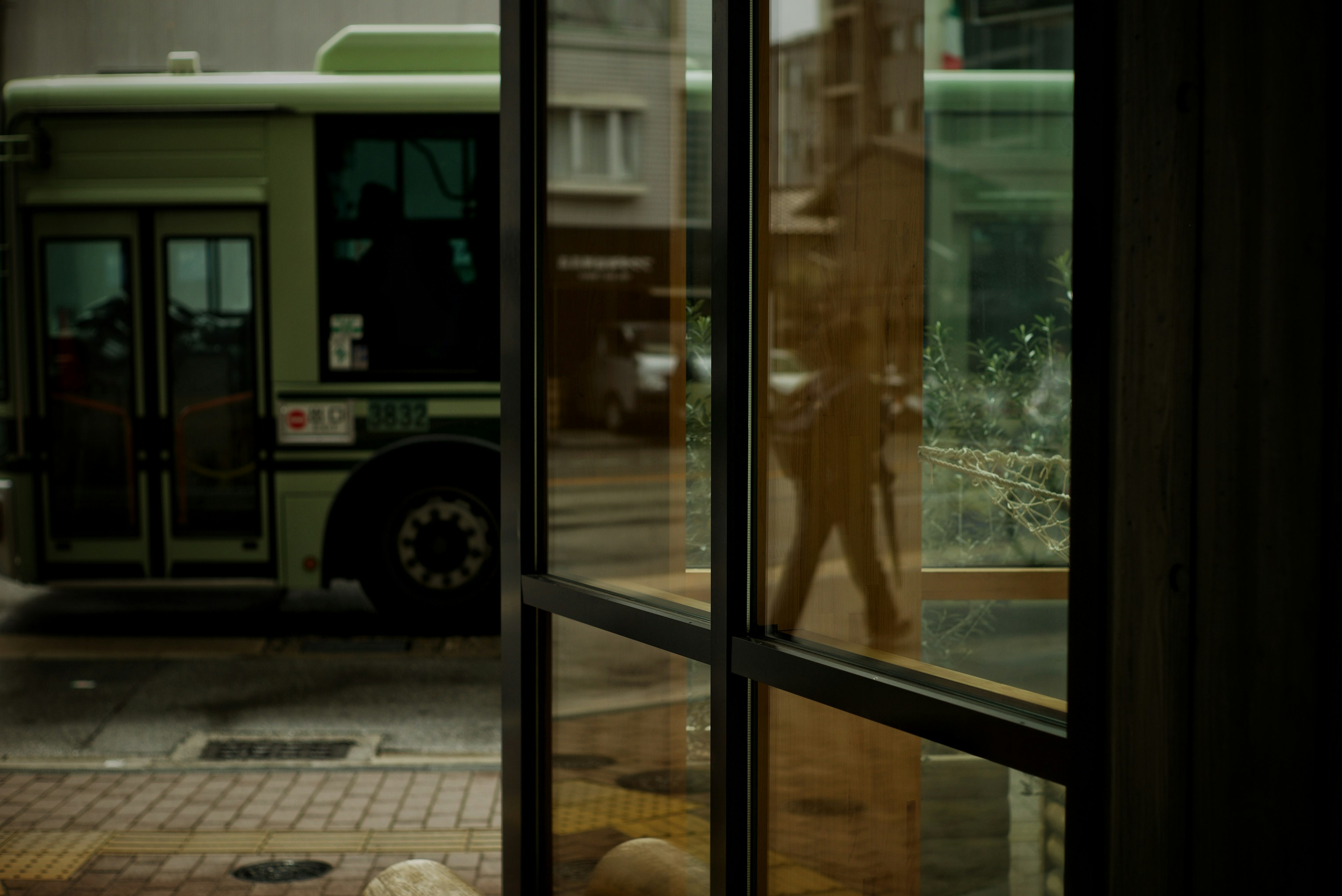 Reflejo de un autobús y un peatón a través de una ventana