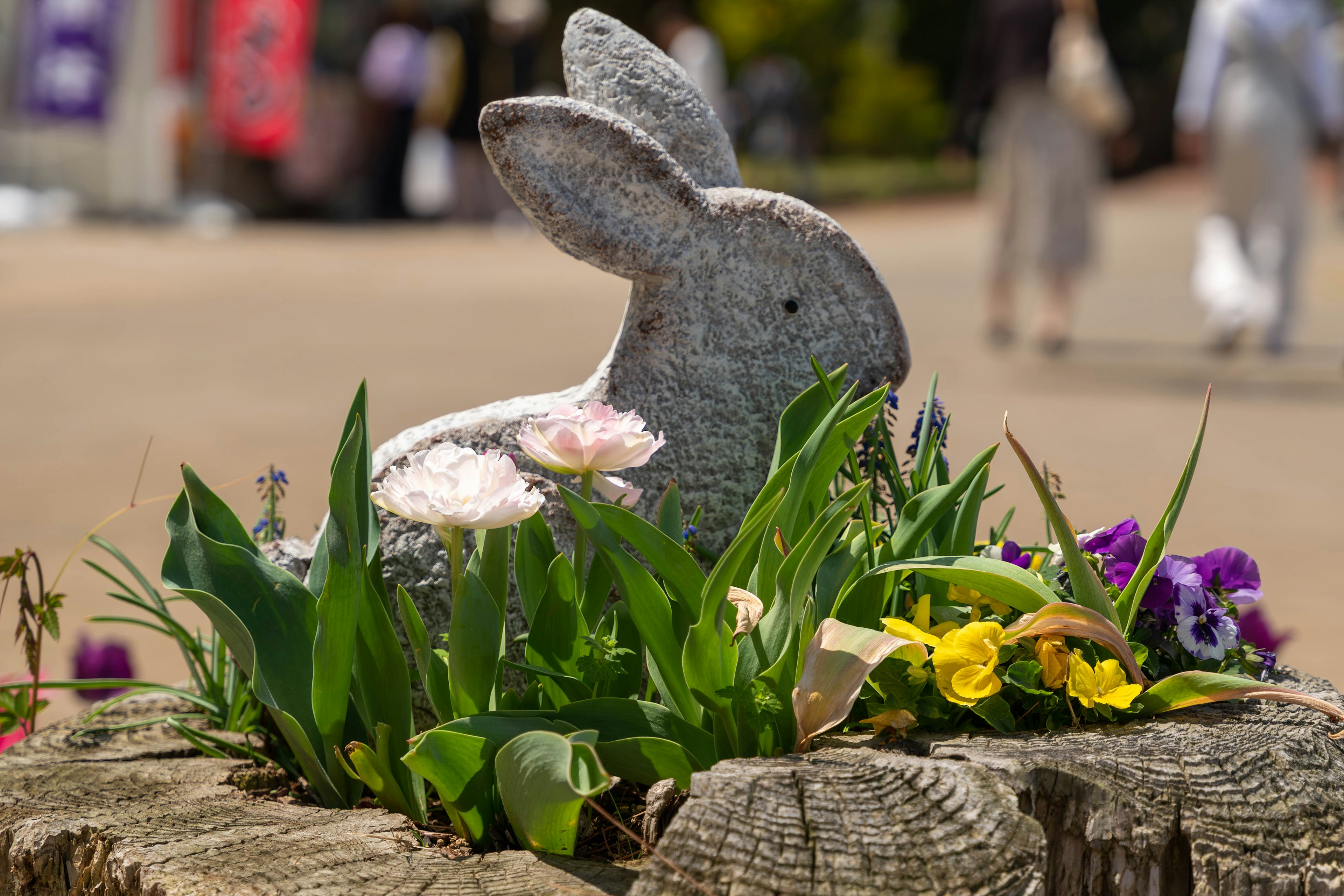 Stein Kaninchenstatue umgeben von bunten Blumen