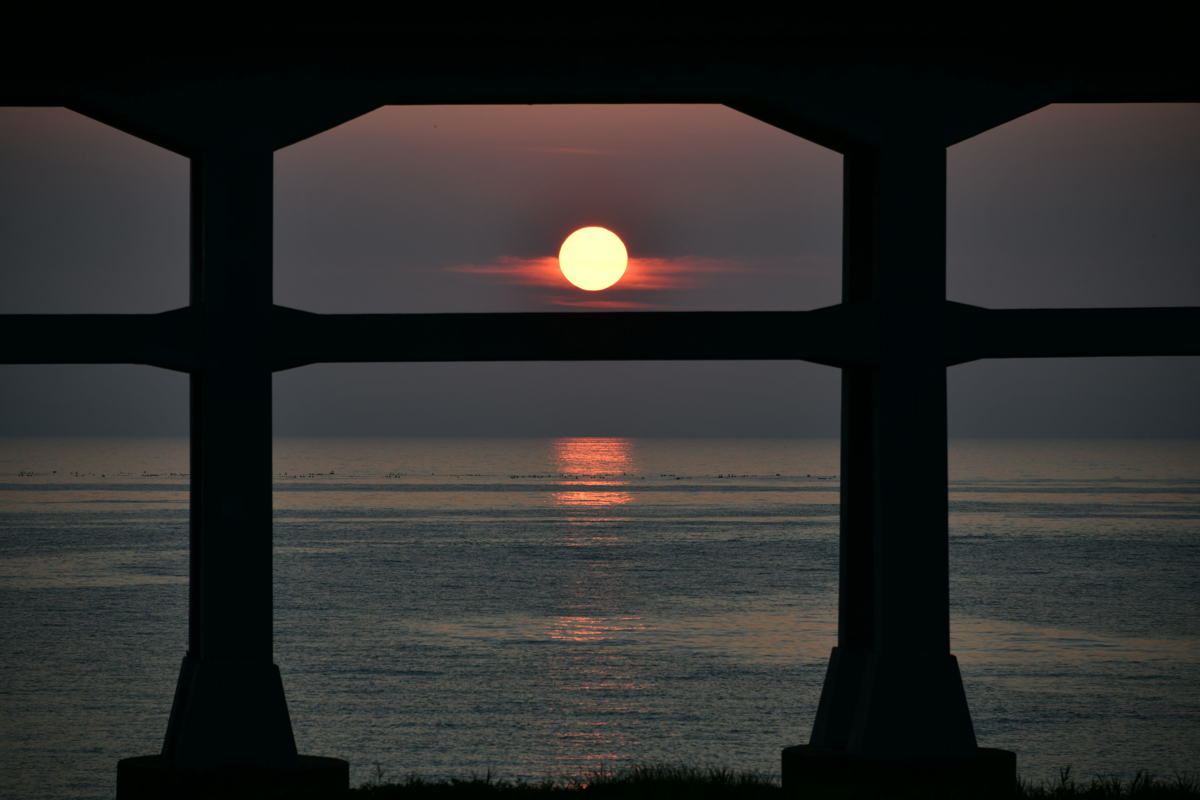 Blick auf den Sonnenuntergang, der sich durch Säulen im Wasser spiegelt