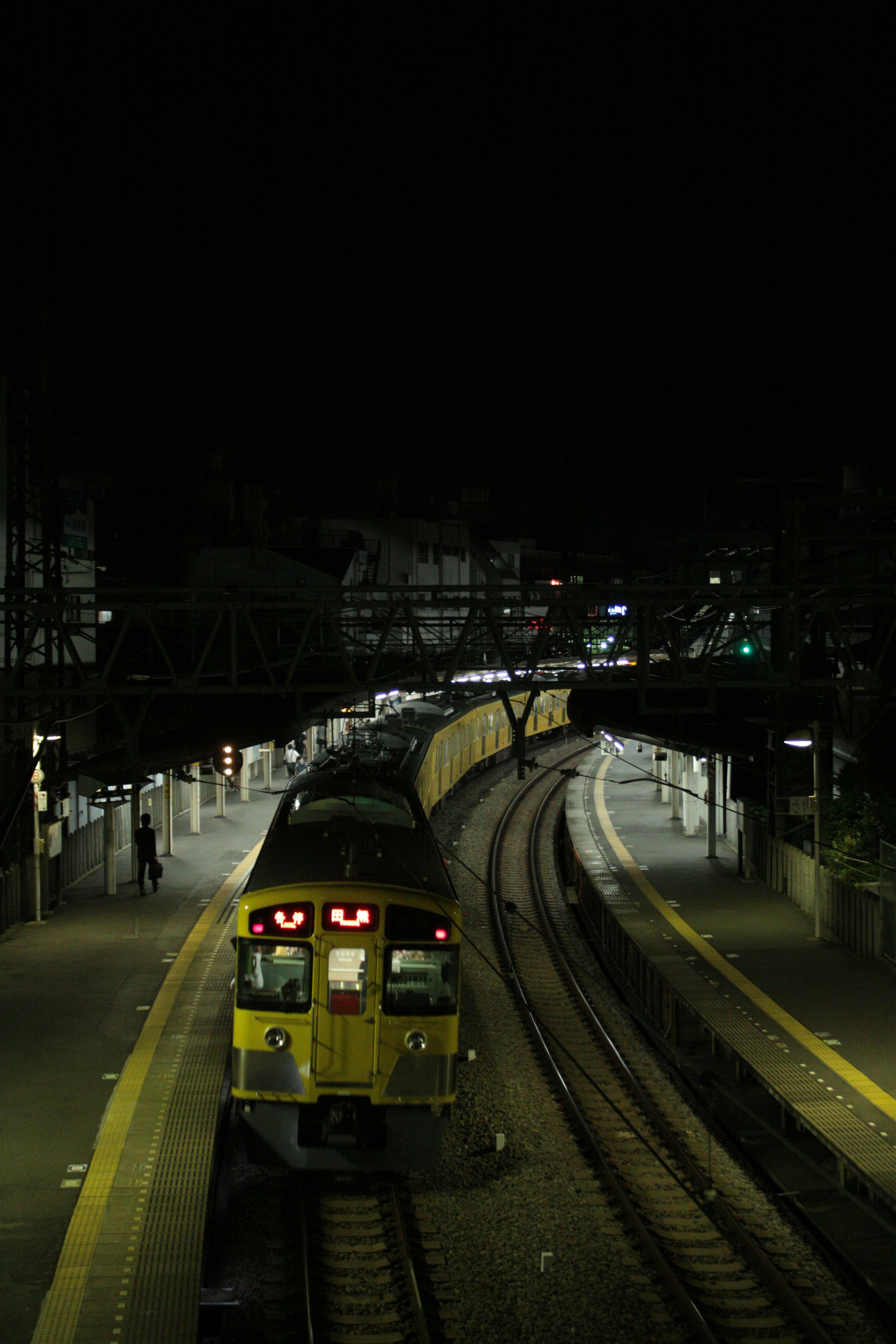 A yellow train stopped at a station at night