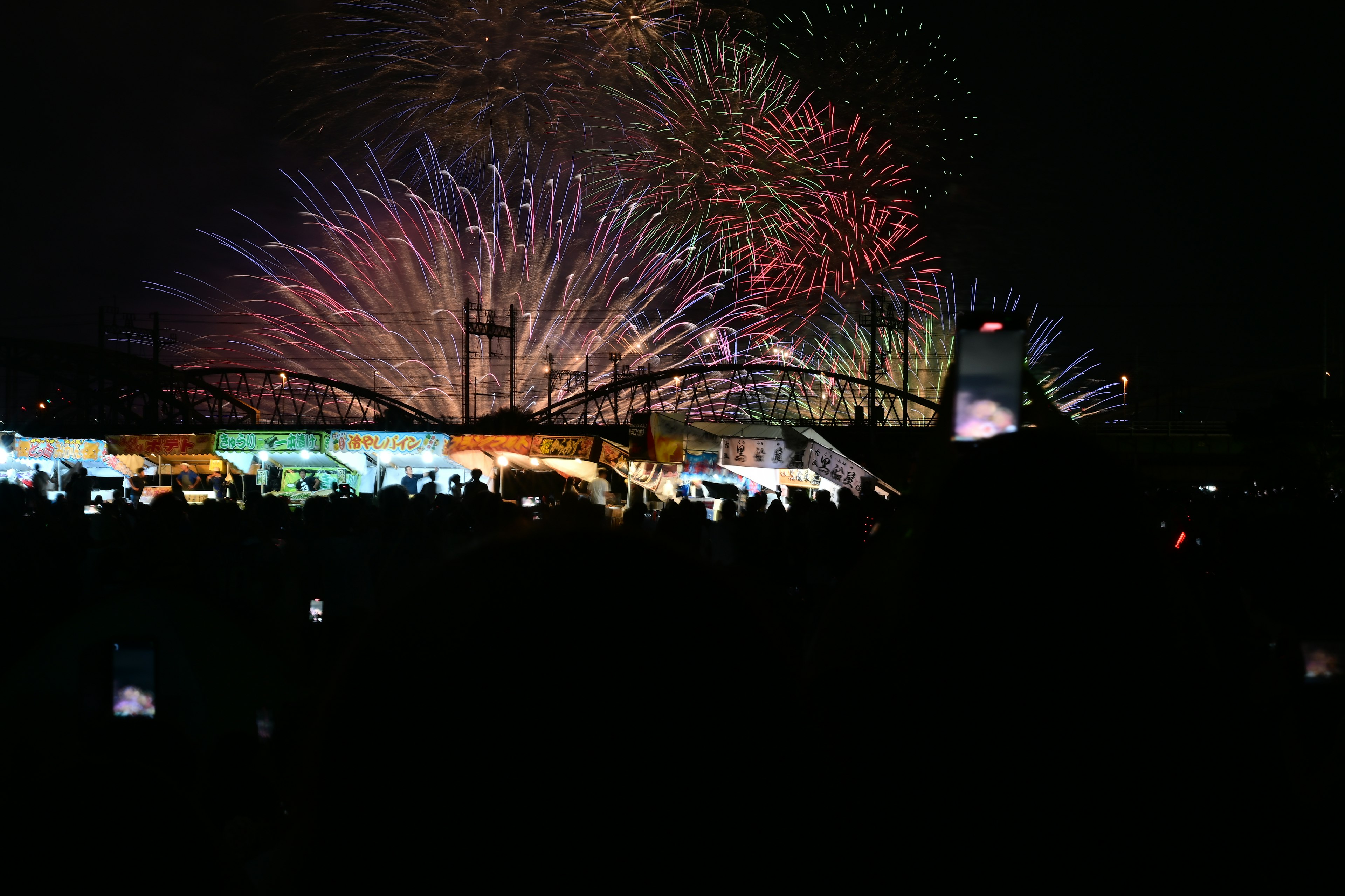 Spectacular fireworks display lighting up the night sky with silhouettes of spectators