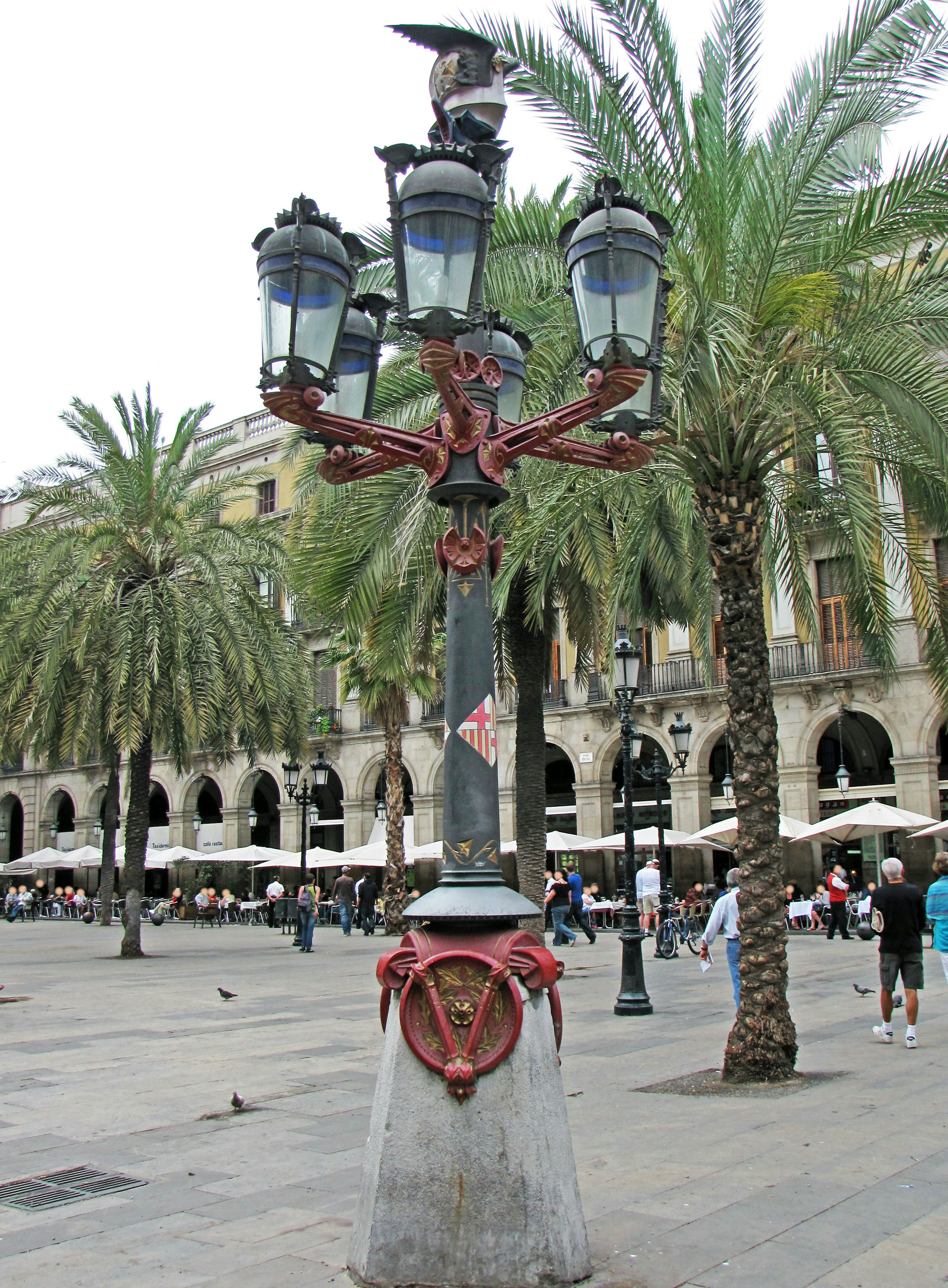 Decorative street lamp in a Barcelona square surrounded by palm trees