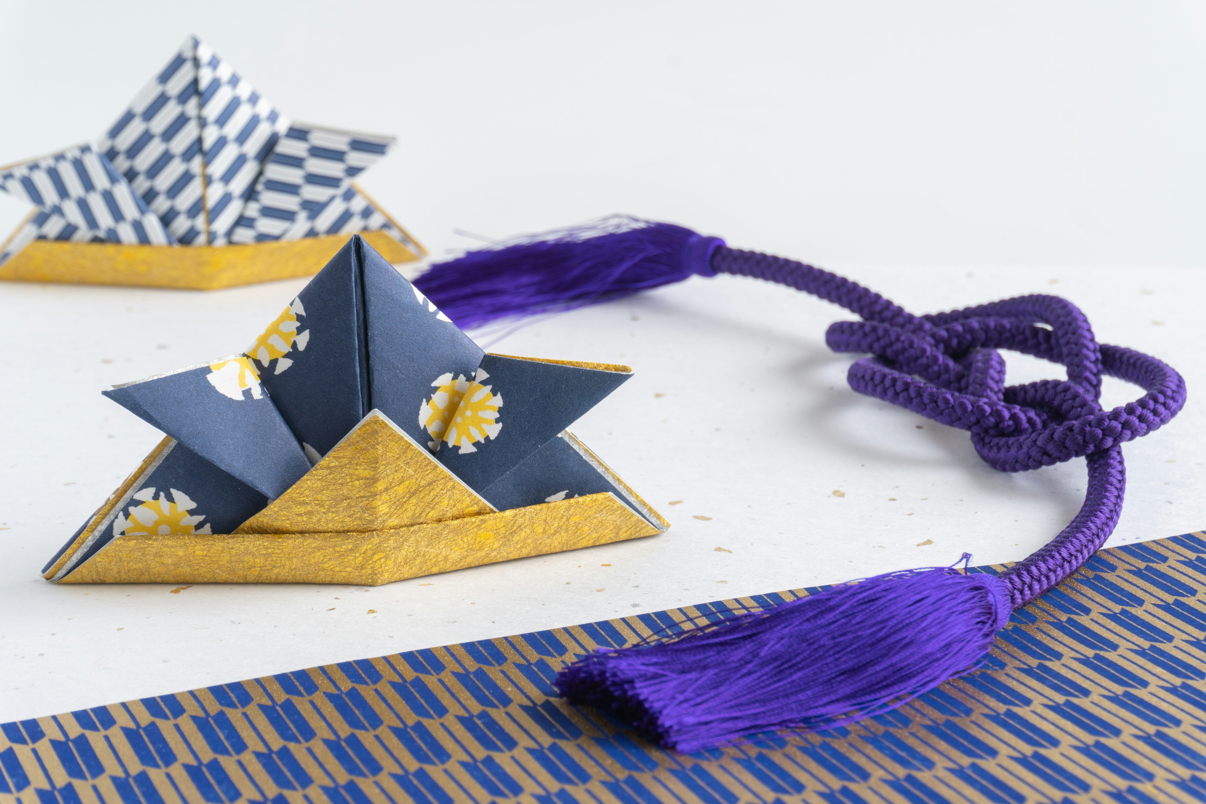 Stelle in origami con motivi blu e bianchi e dettagli dorati con un pon-pon viola