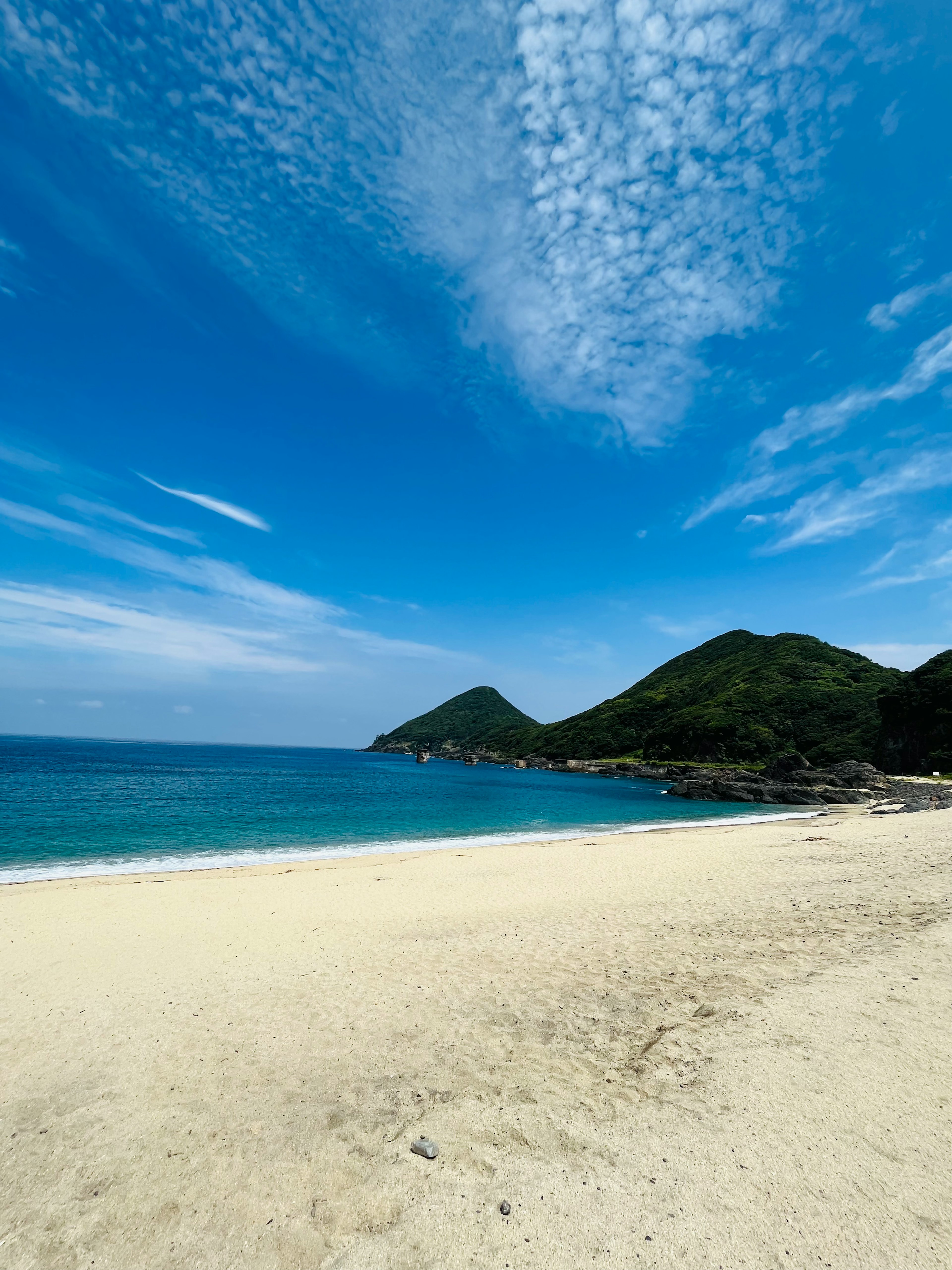 青い海と空が広がるビーチの風景 緑の山々が背景にある