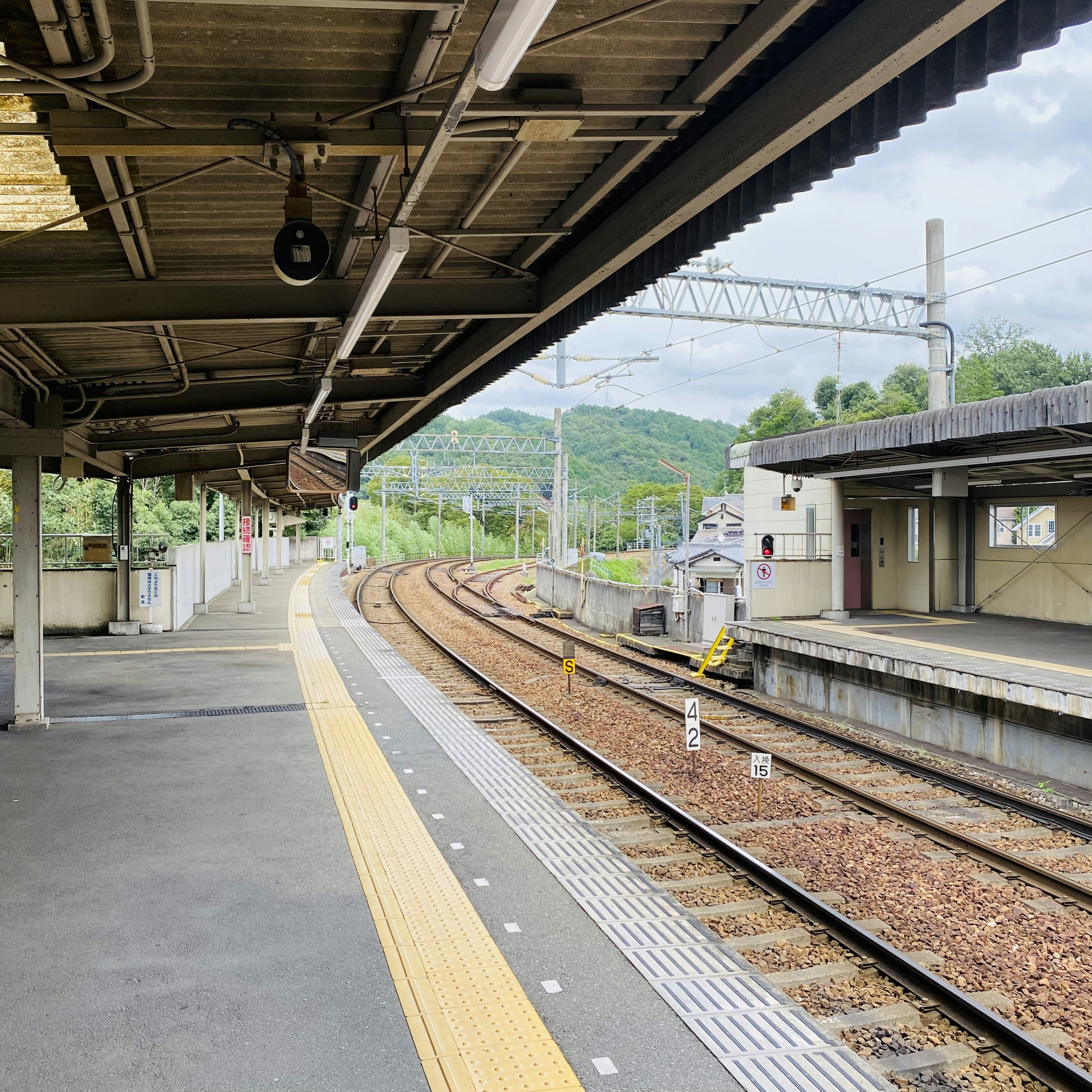 Quiet train station platform with curving tracks visible