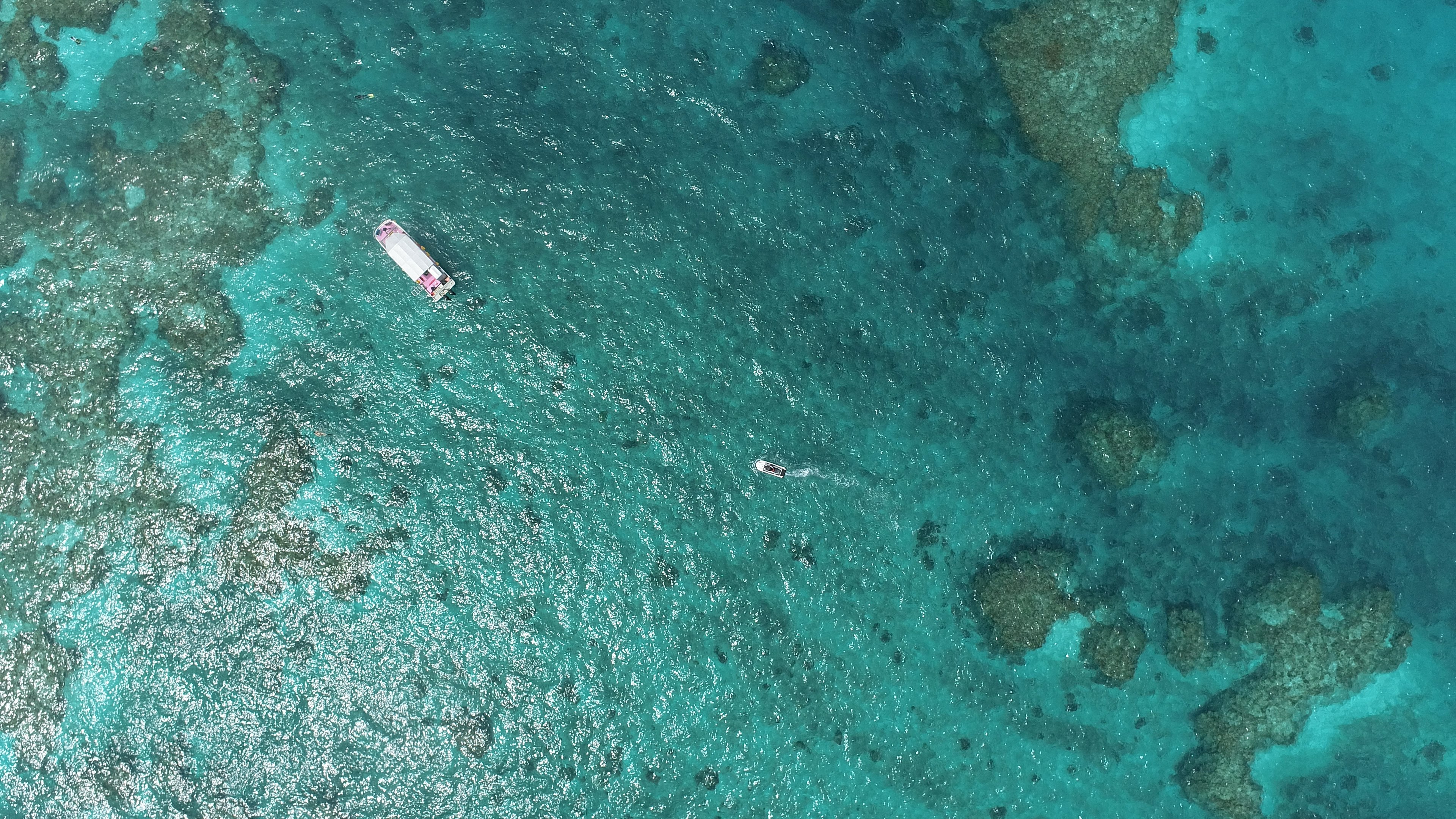 Sebuah perahu mengapung di lautan biru dengan terumbu karang