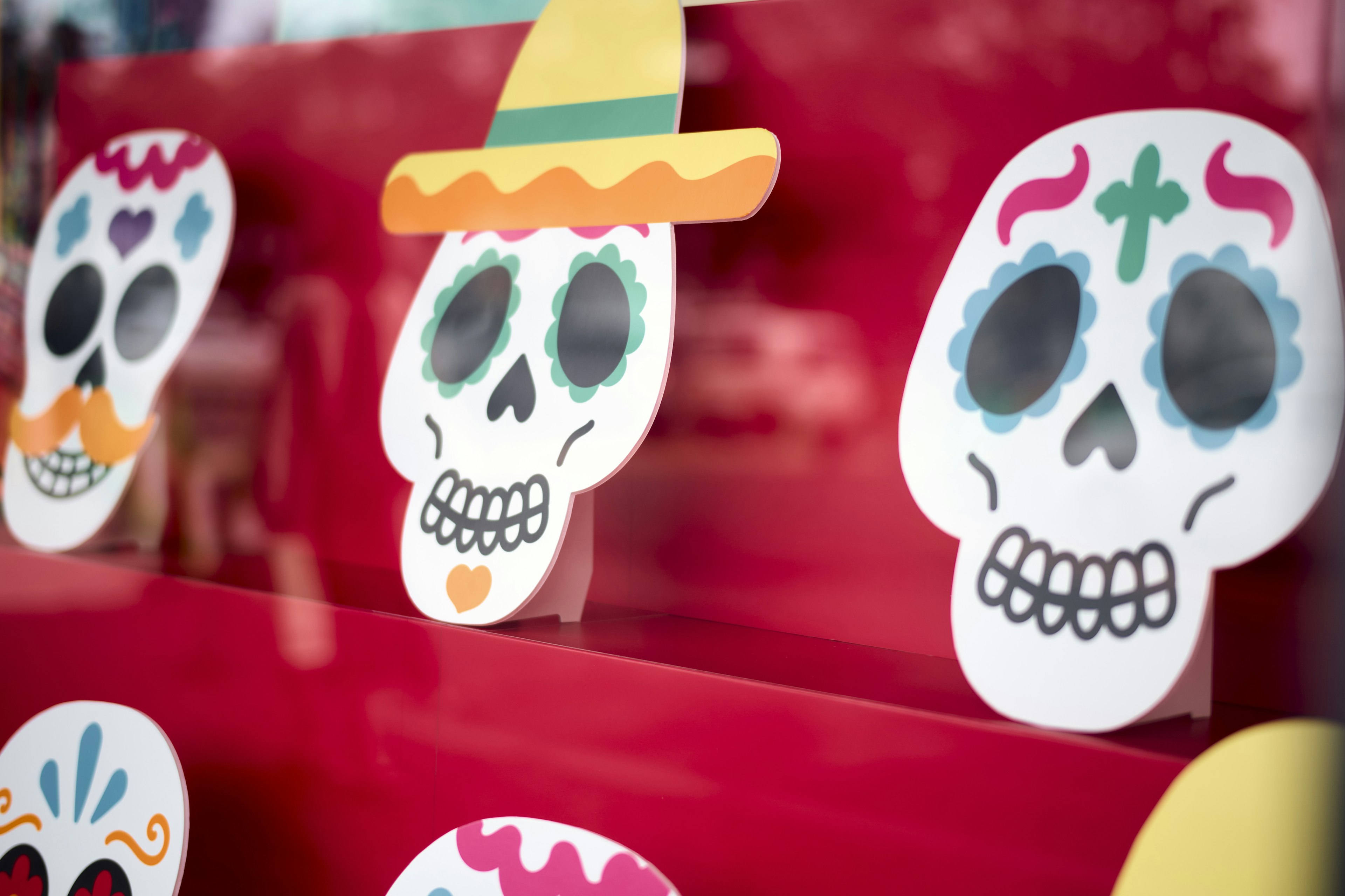 Decoraciones de calaveras coloridas exhibidas sobre un fondo rojo