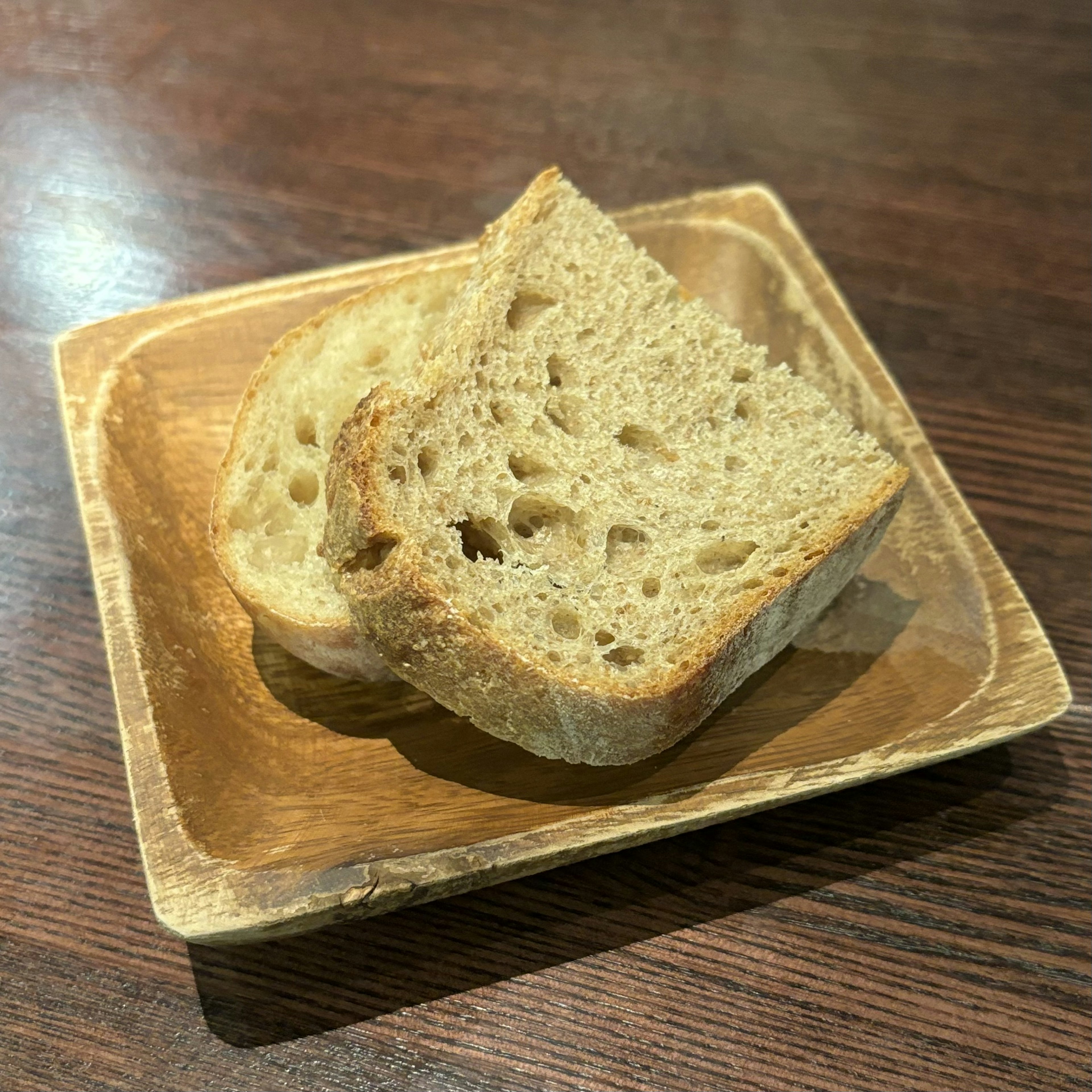 Two slices of whole grain bread on a wooden plate