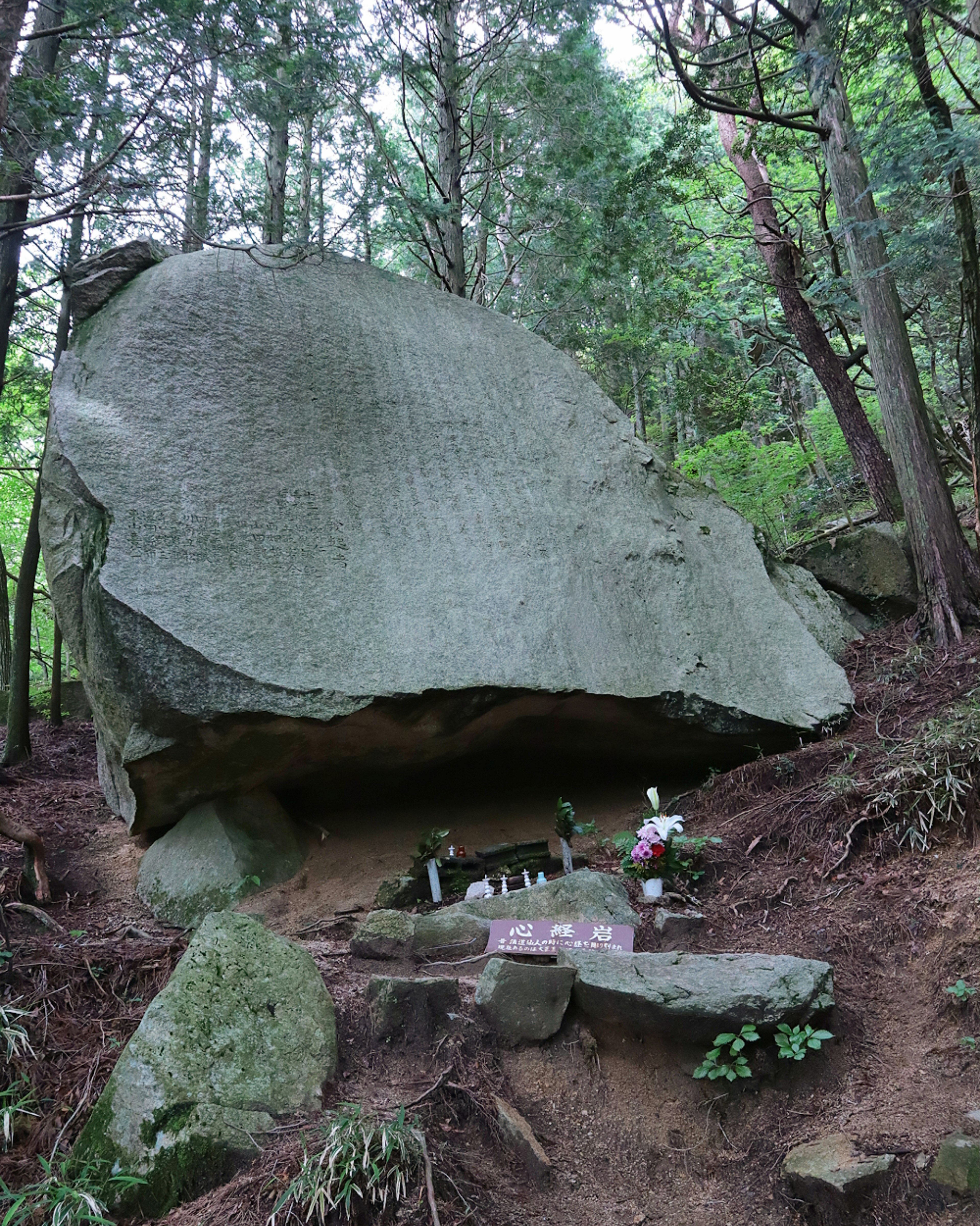 A large rock with a small shrine surrounded by forest