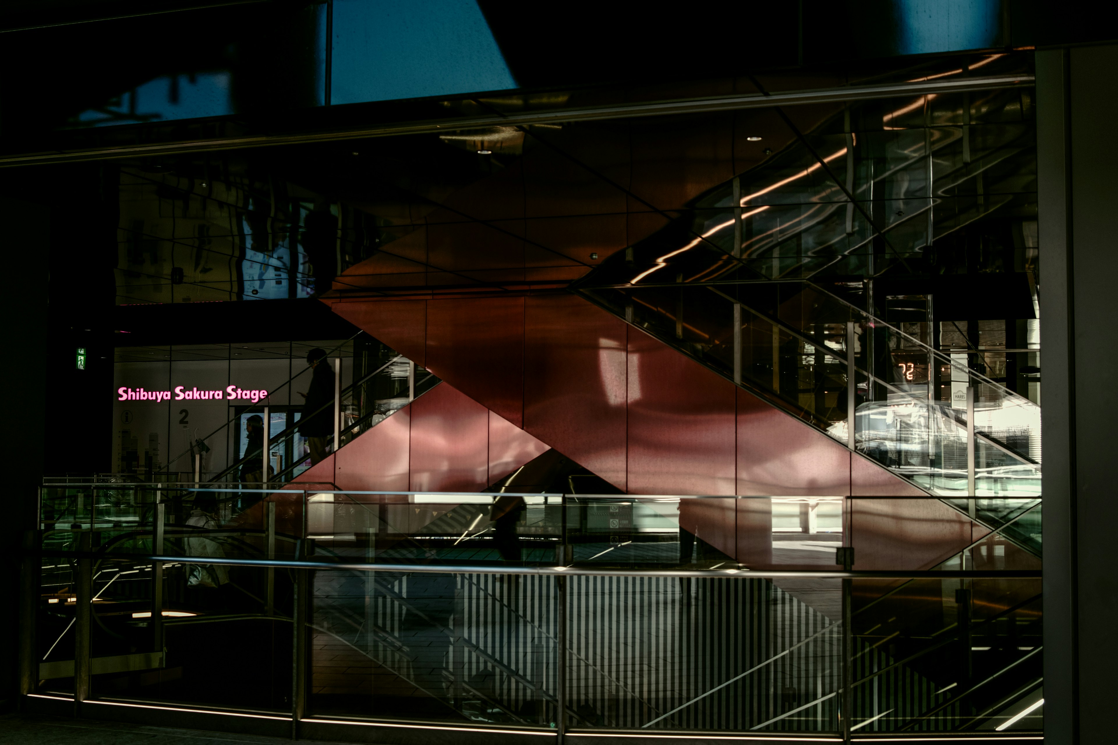 Modern building interior with glass facade featuring red staircase and lighting