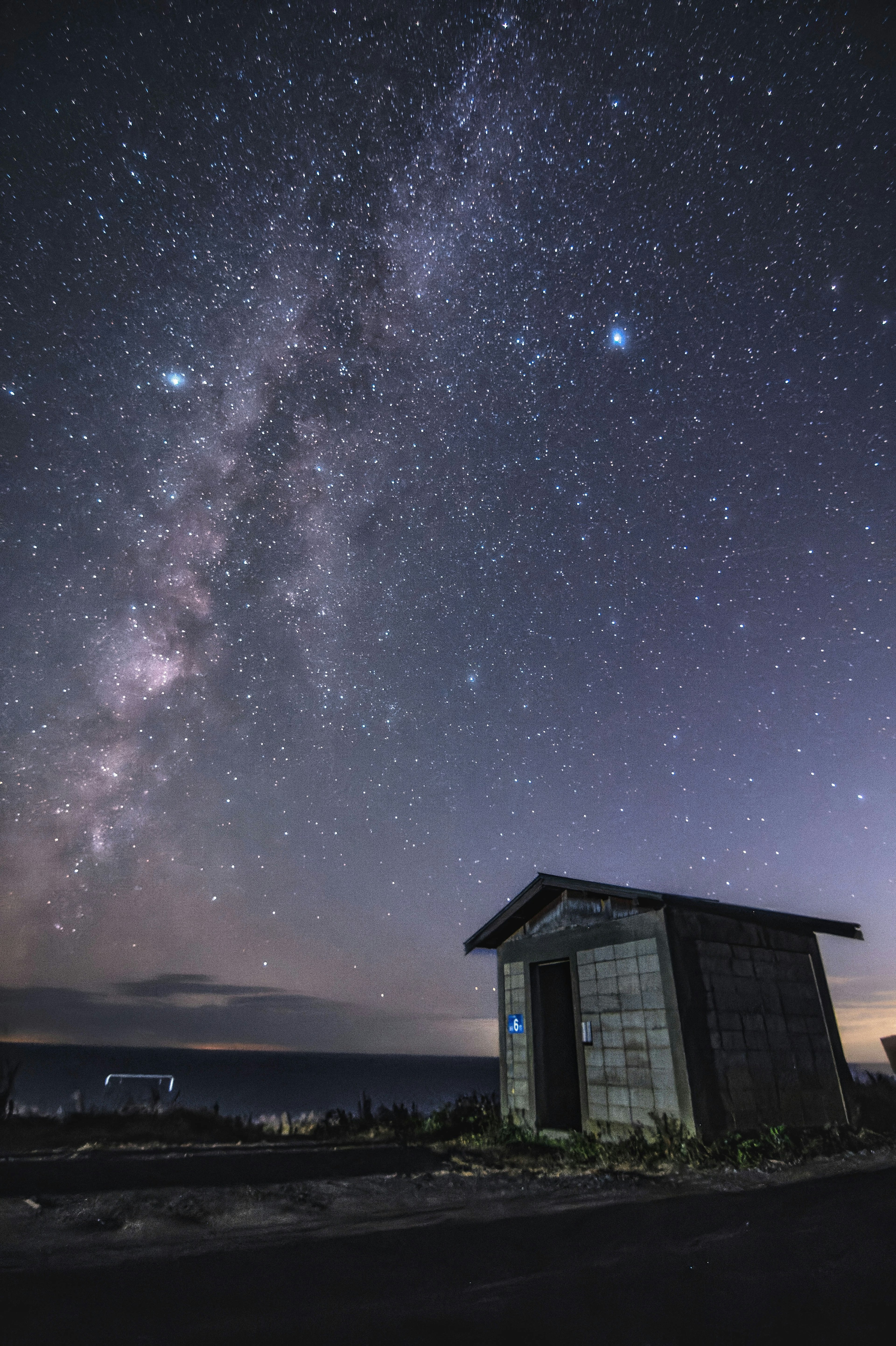 A small hut under a starry sky featuring a bright Milky Way