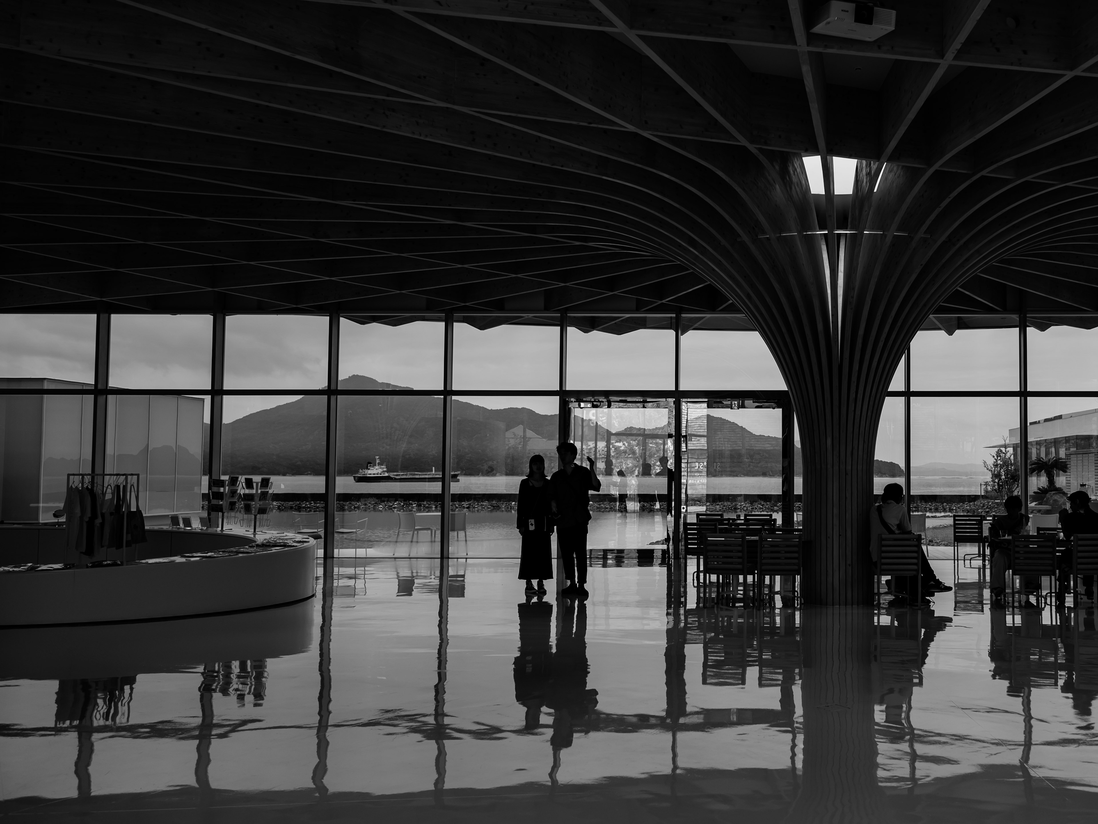 Silhouettierte Paar steht in einer modernen Flughafenlobby mit Bergblick