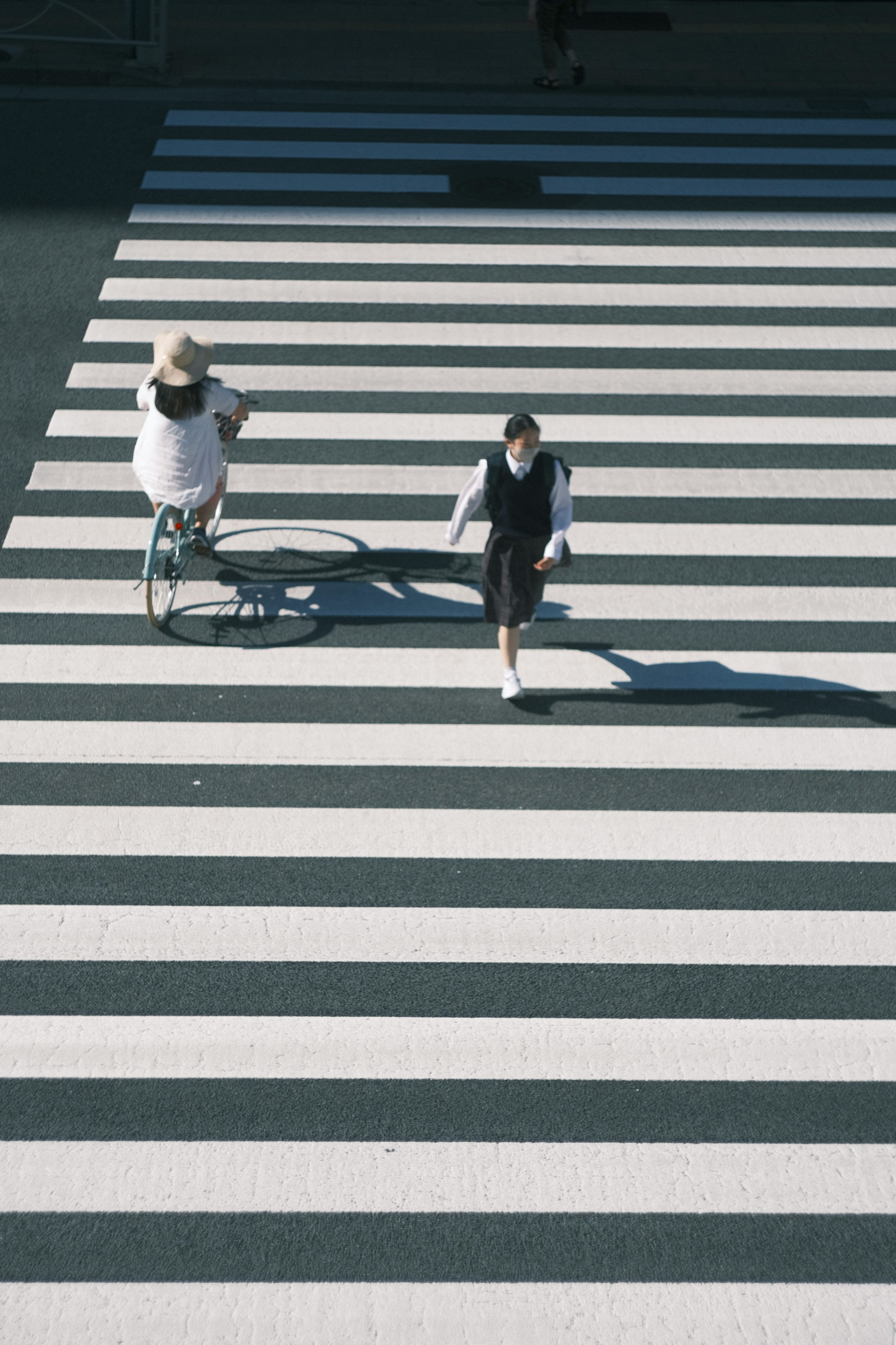 Bicicletta e pedone che attraversano un attraversamento pedonale bianco e nero