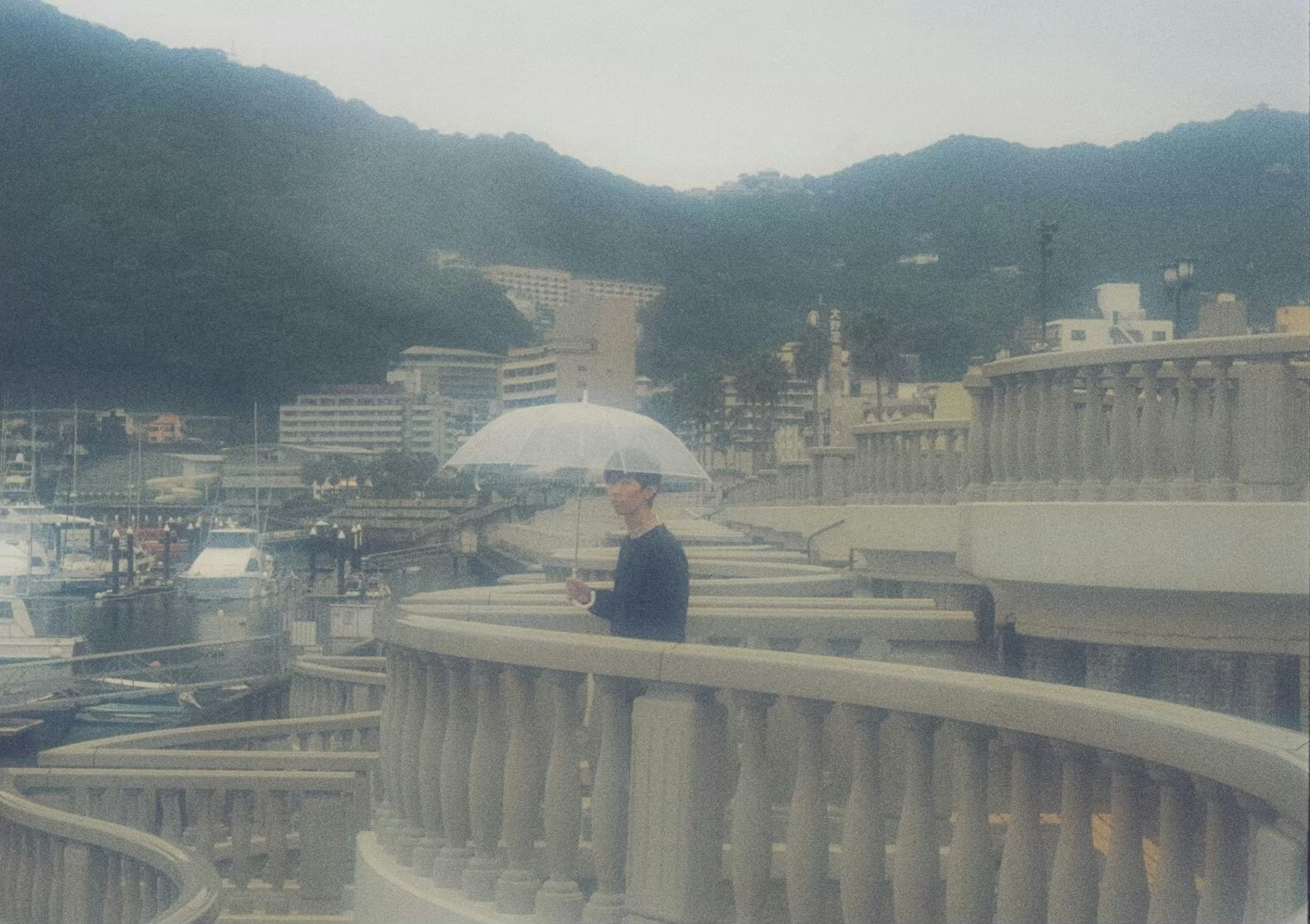 Person walking along a coastal path holding an umbrella