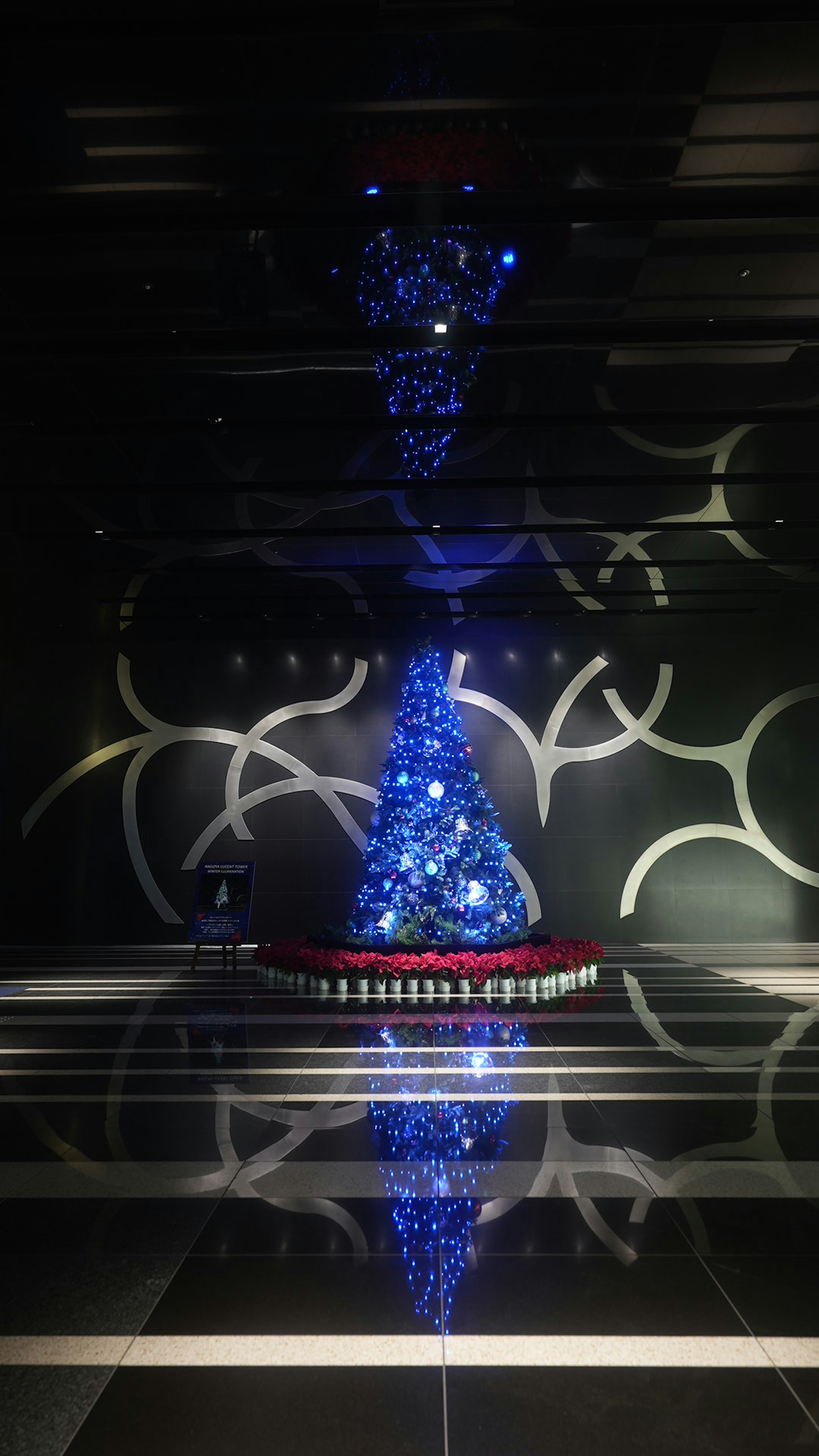 Unique Christmas tree decorated with blue lights reflecting in modern interior