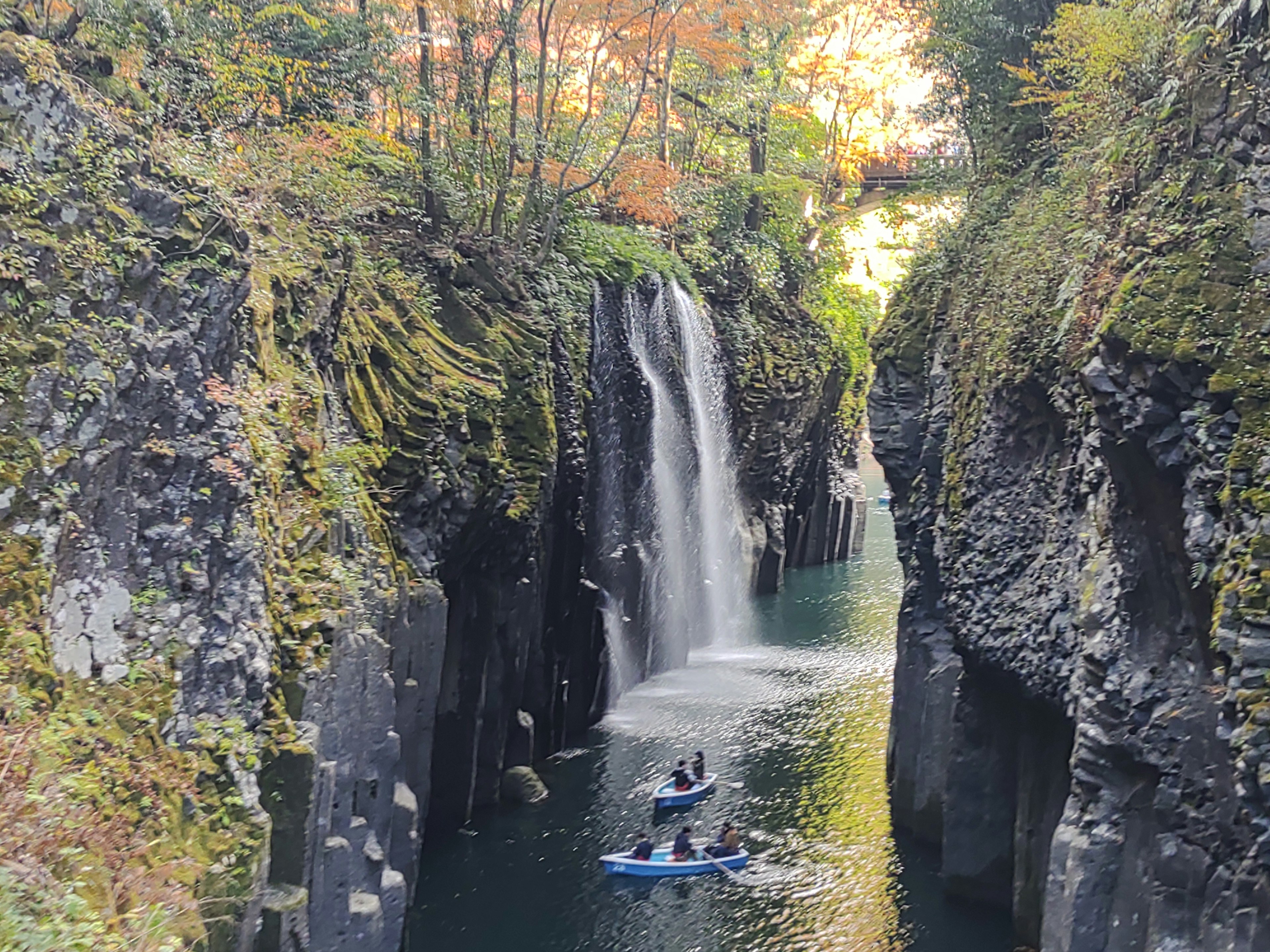 Scenic view of kayakers navigating a canyon with a waterfall