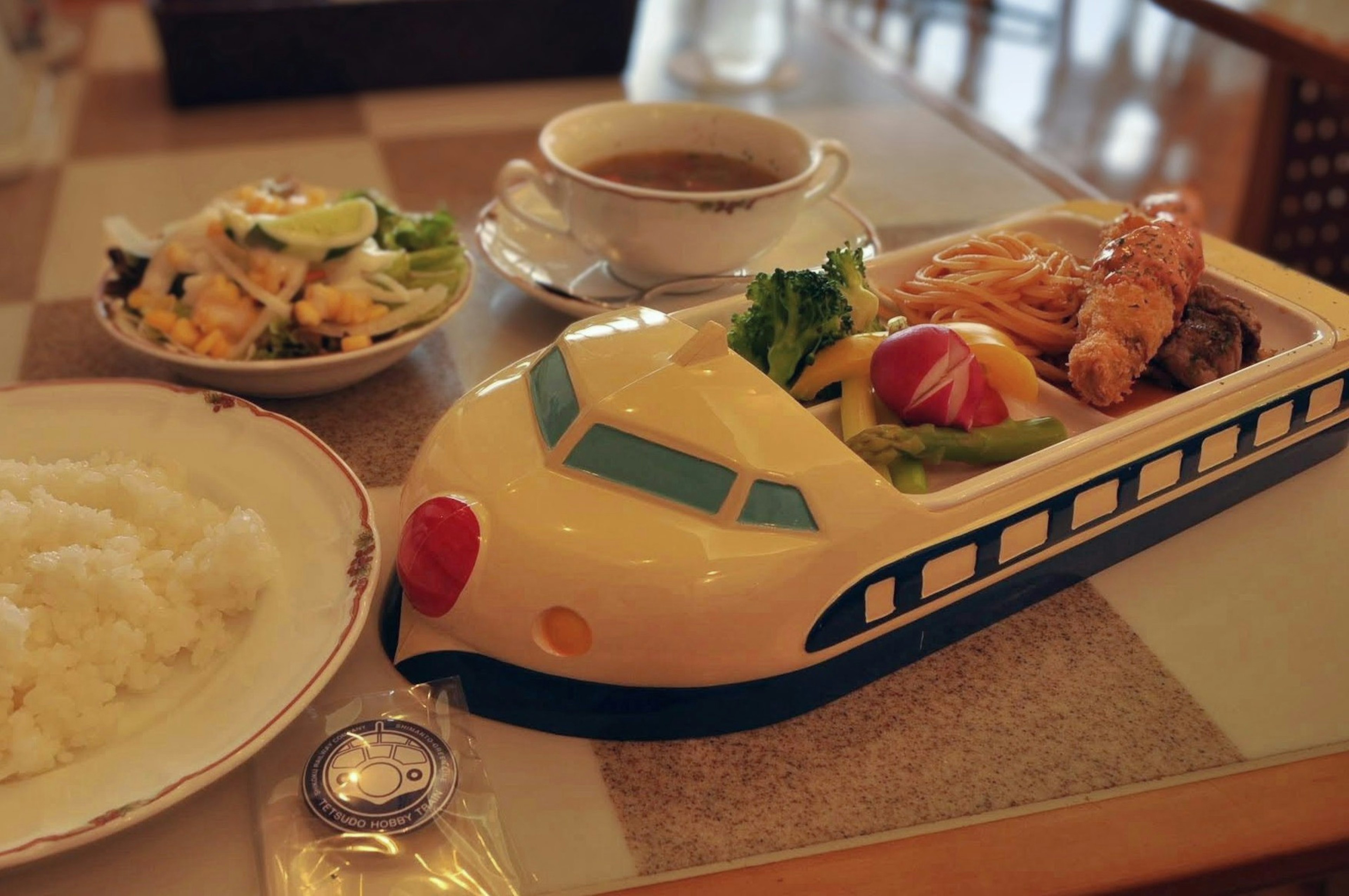 Comida servida en un plato con forma de tren con ensalada y arroz