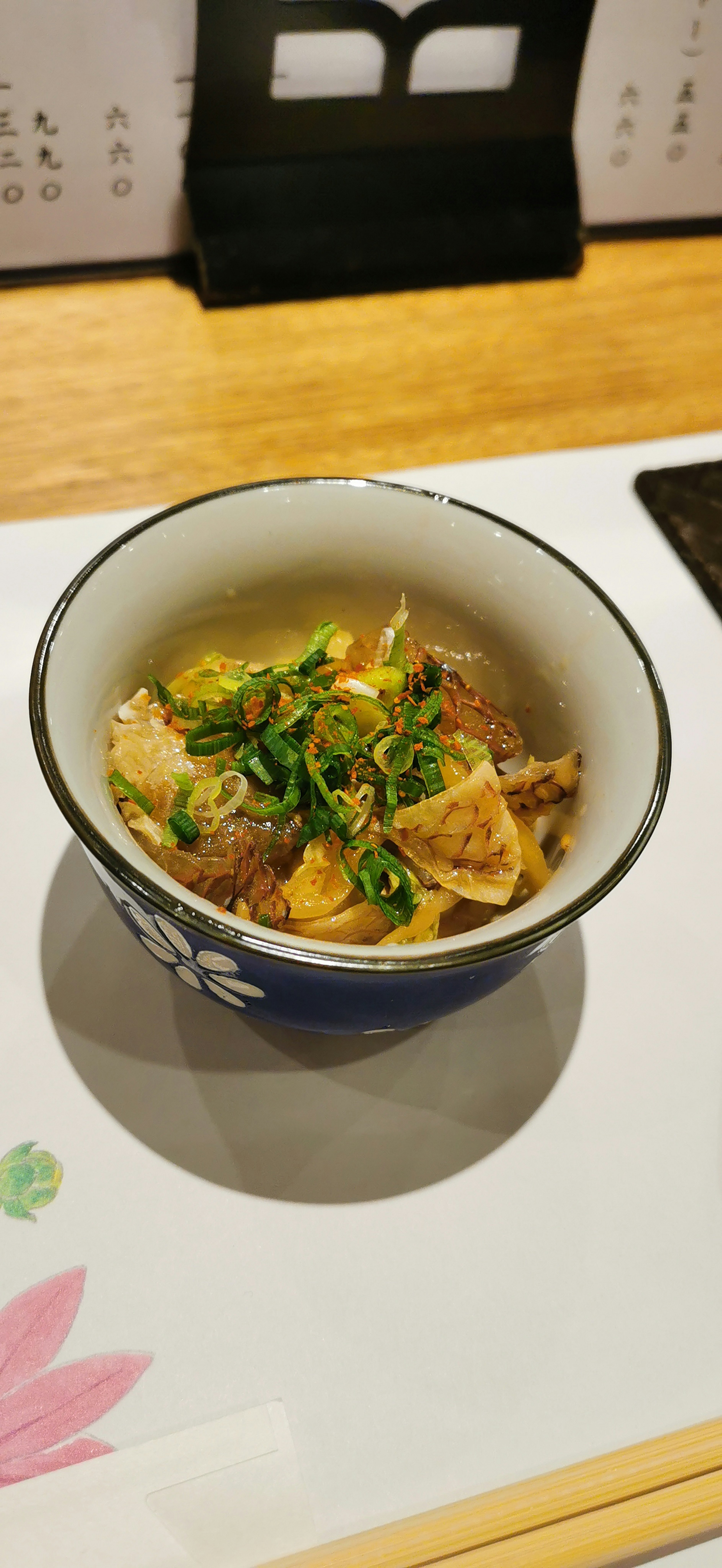 Un pequeño tazón de plato japonés cubierto con cebollas verdes