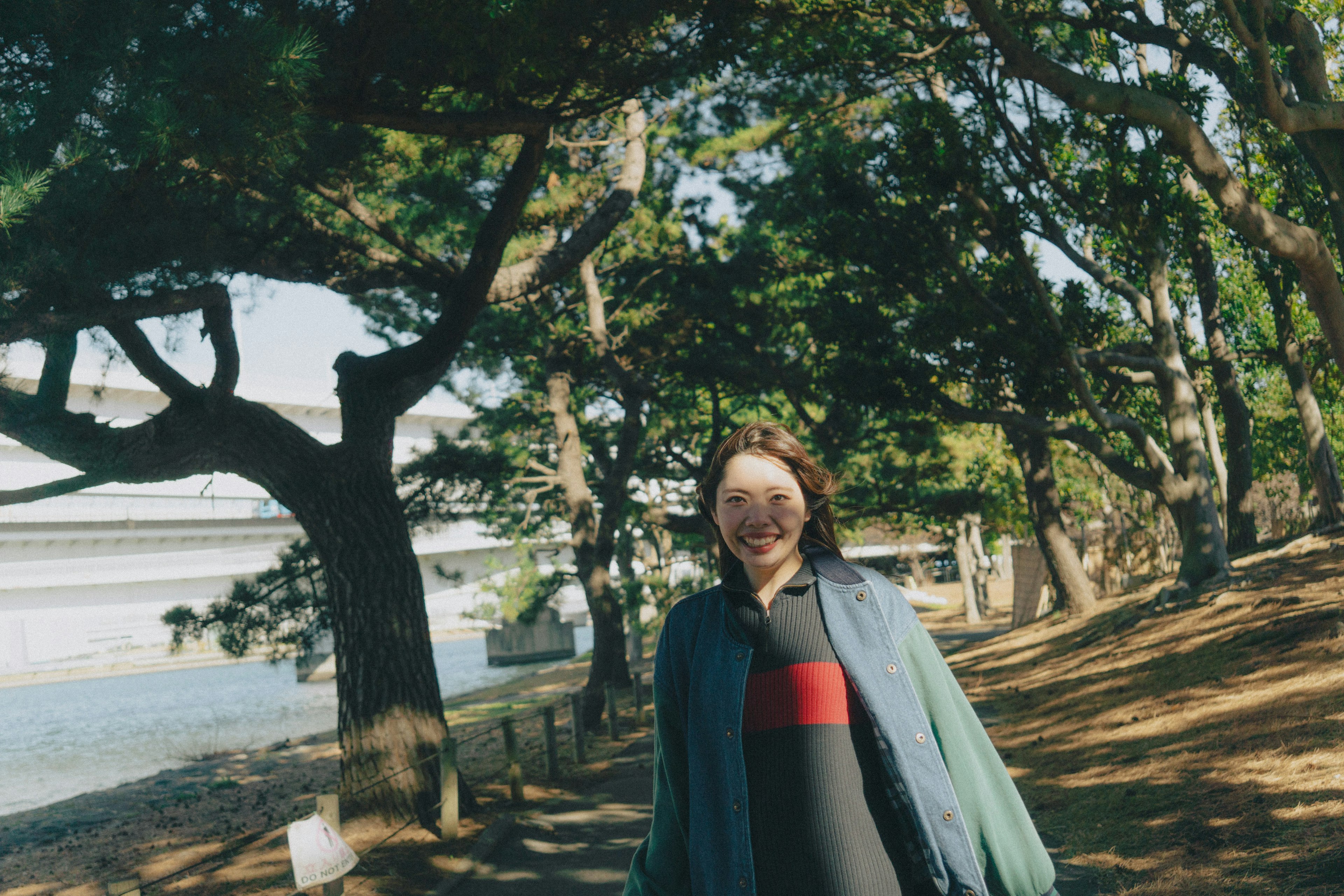 Donna sorridente in cappotto verde tra gli alberi