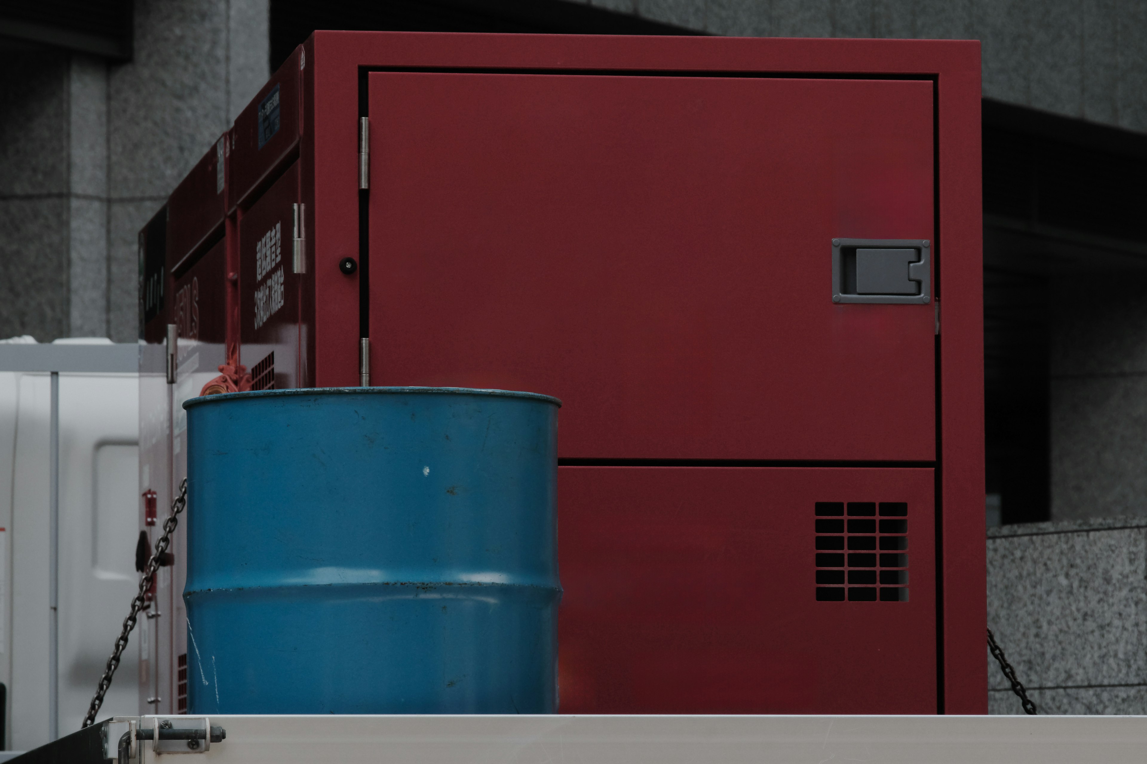 Red storage unit next to a blue drum in an industrial setting