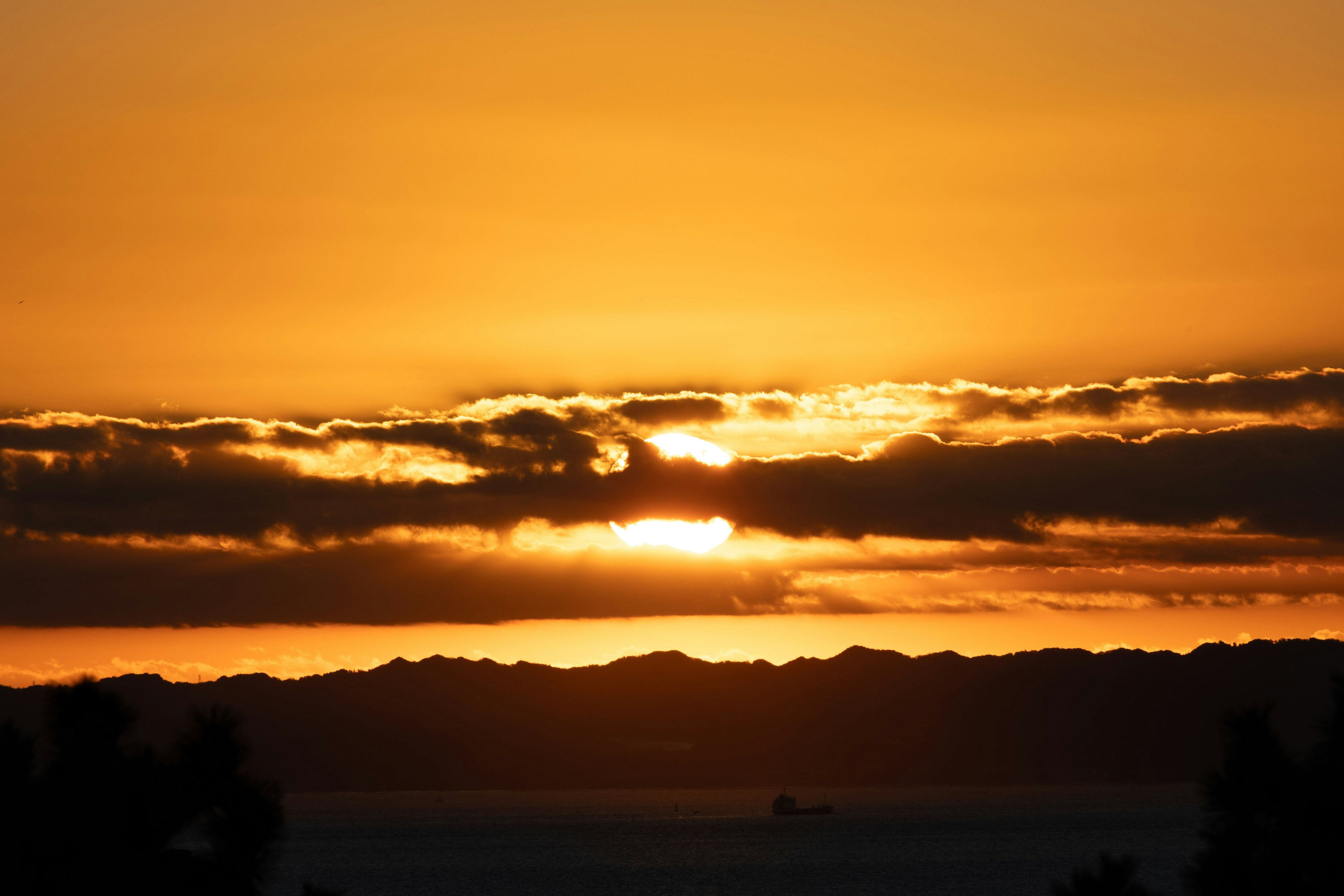 美しいオレンジ色の夕日が雲の間から顔を出している風景
