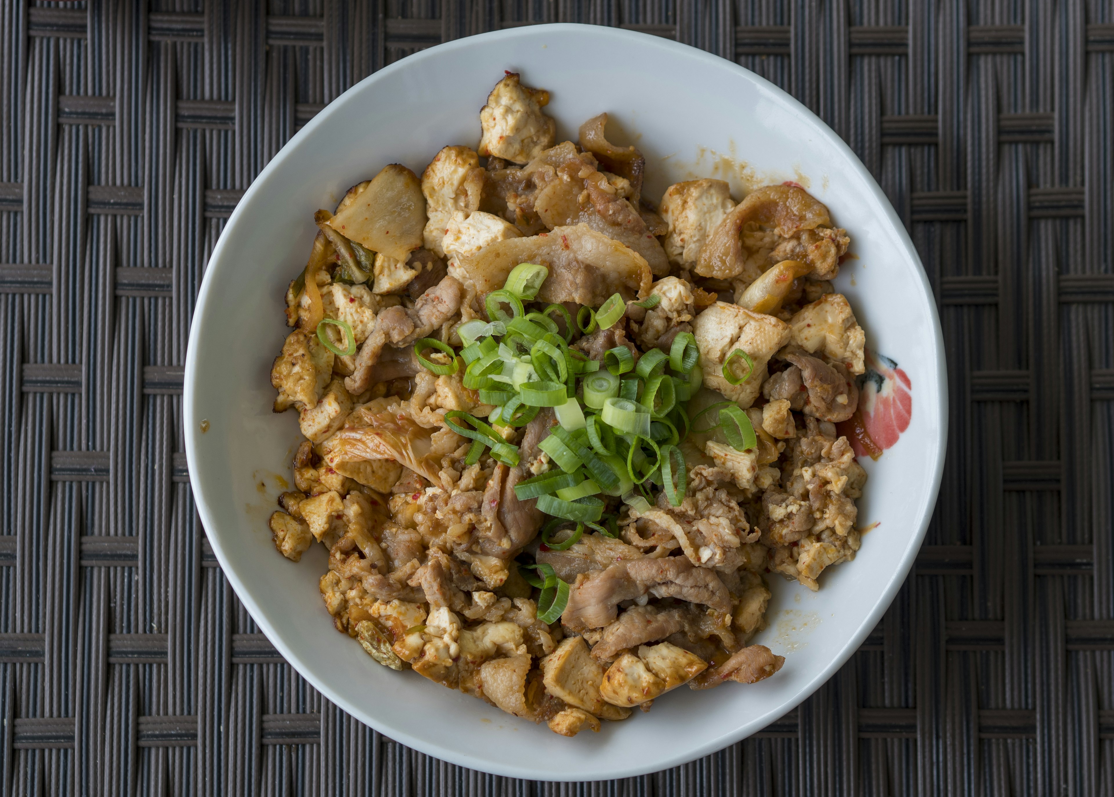 Un bol de riz au poulet et œufs savoureux garni d'oignons verts