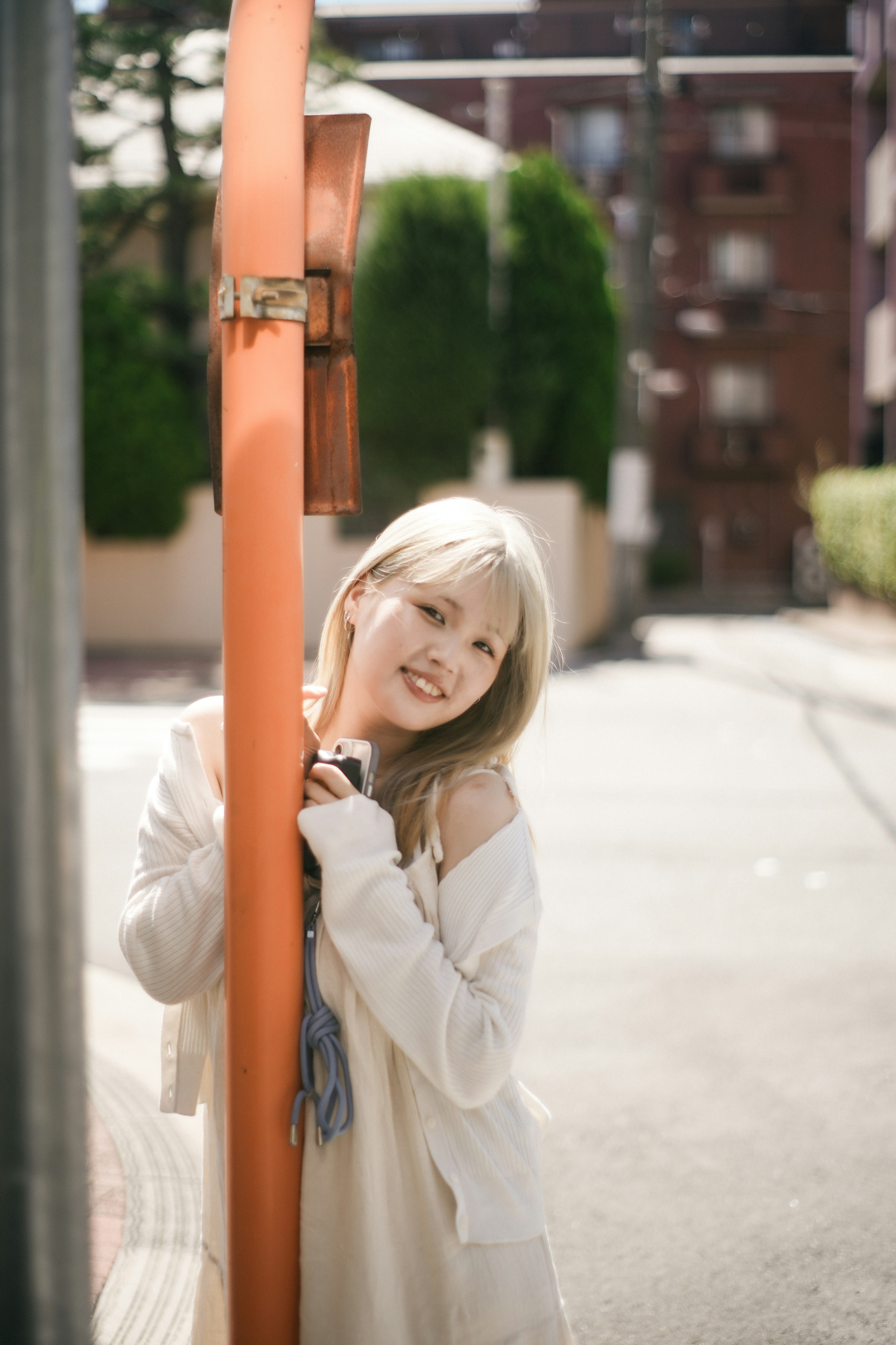 Mujer joven apoyada en un poste naranja sonriendo