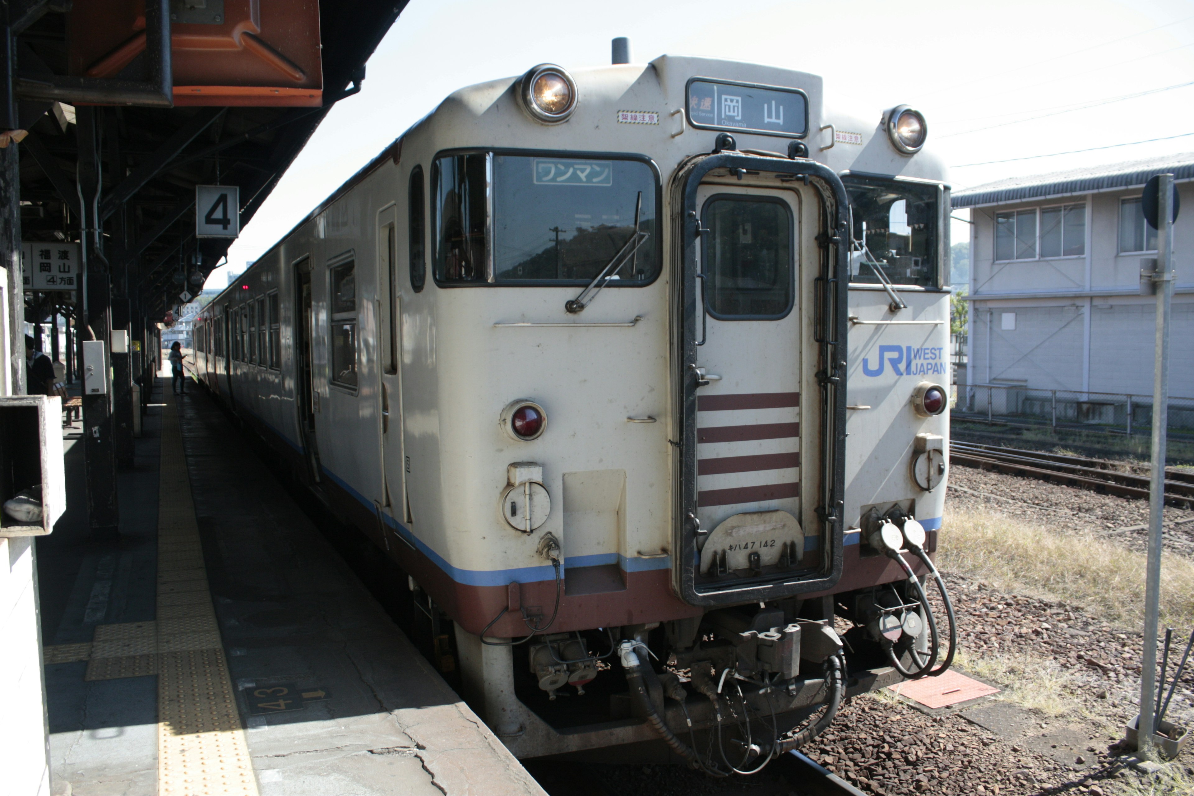 Tren blanco detenido en una estación con paisaje alrededor