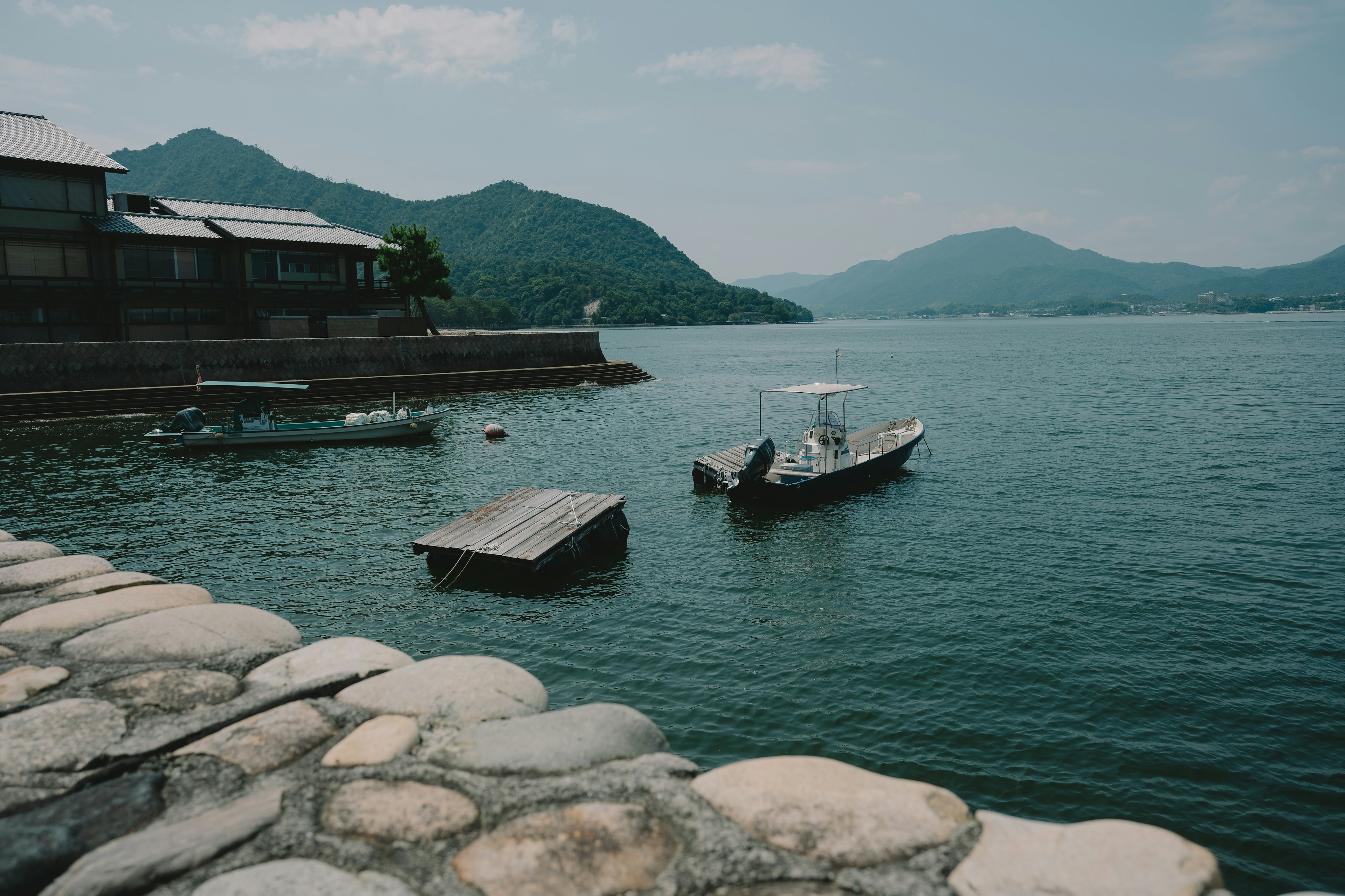 静かな海と山々の風景に浮かぶ小舟と桟橋