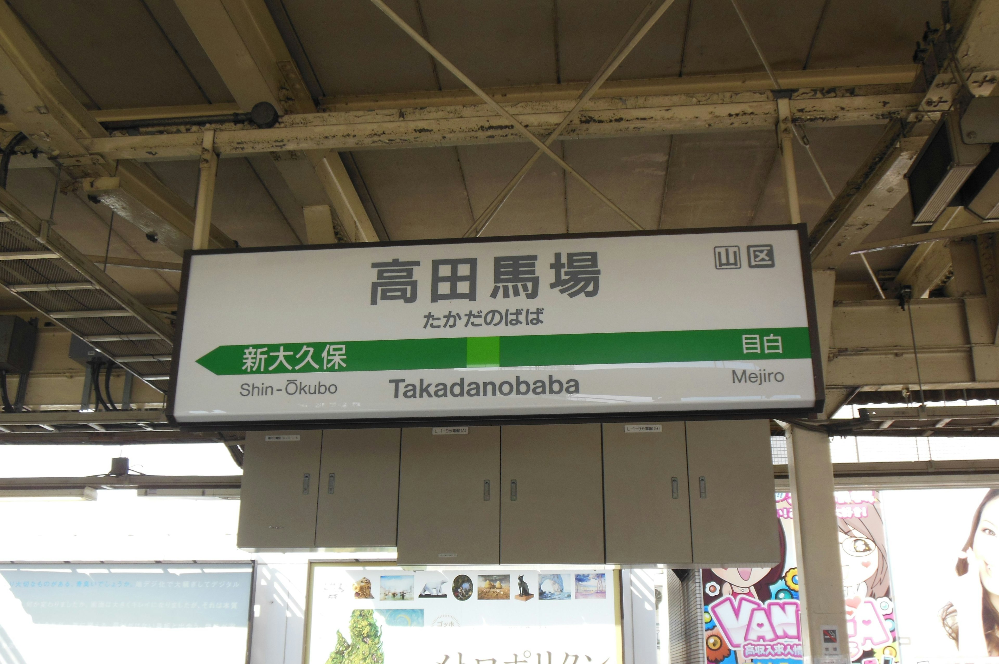 Signage for Takadanobaba Station with green directional arrow