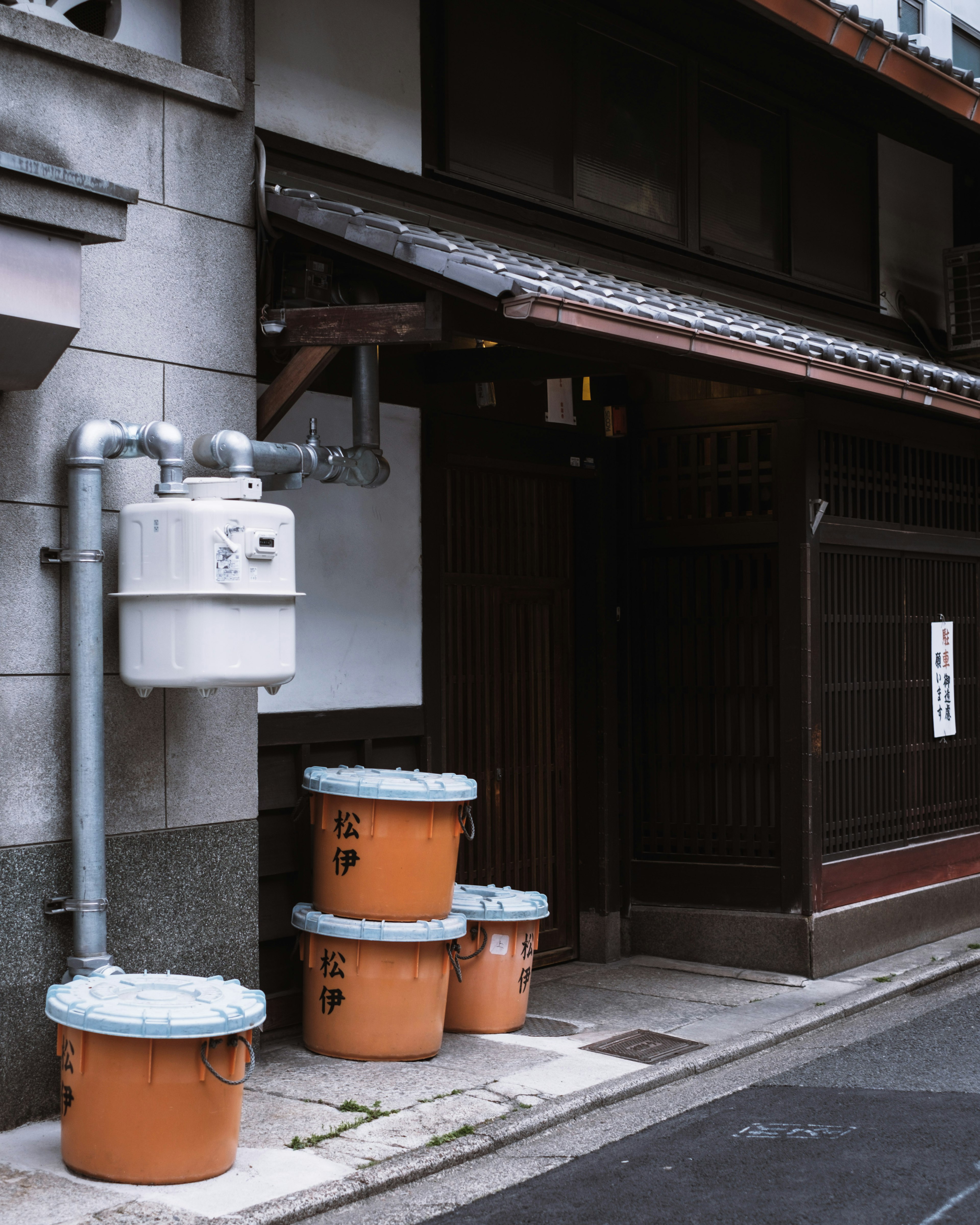 Fachada de un antiguo edificio japonés con cubos de basura naranjas alineados