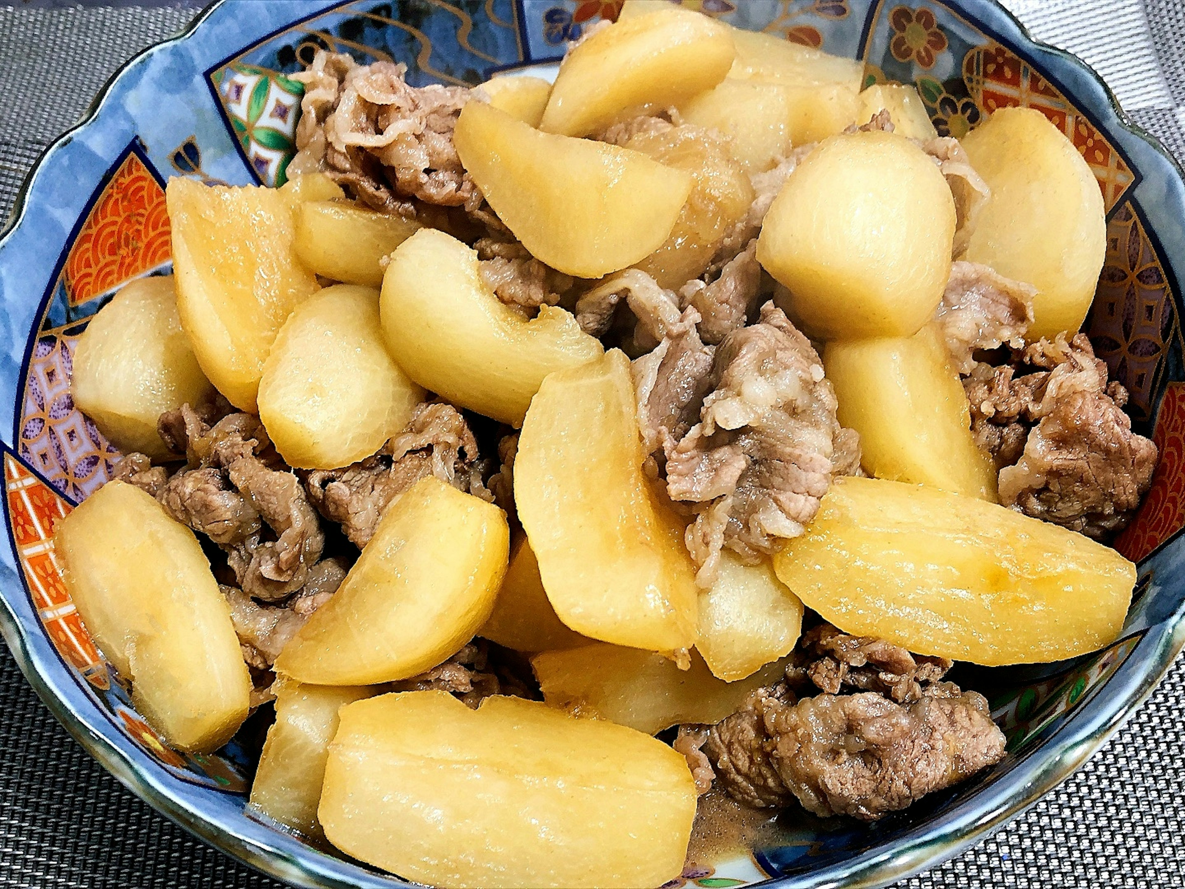 Una ciotola piena di patate dolci e carne in un piatto colorato