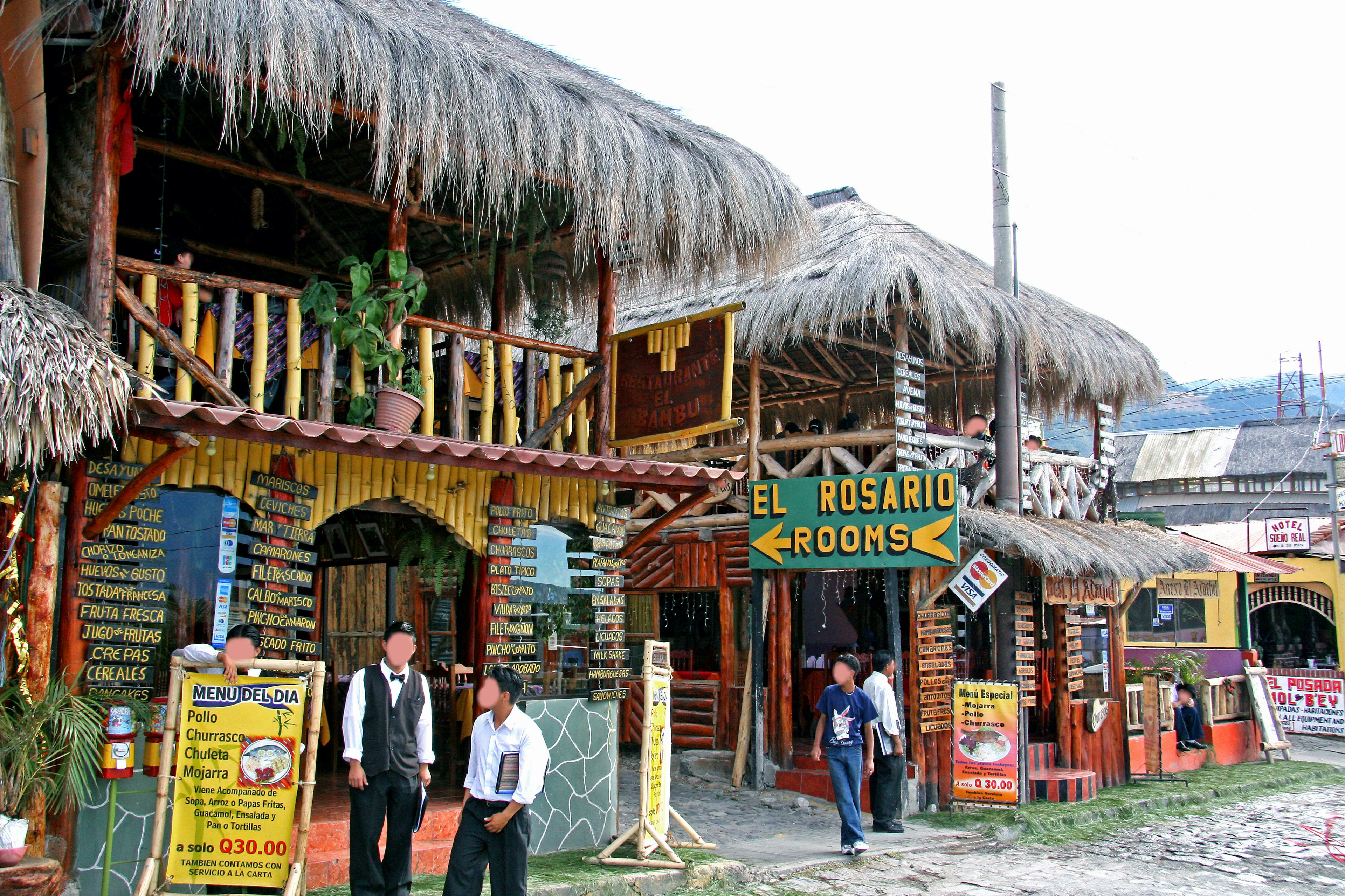 Edificios de madera coloridos con techos de paja y personas de pie afuera