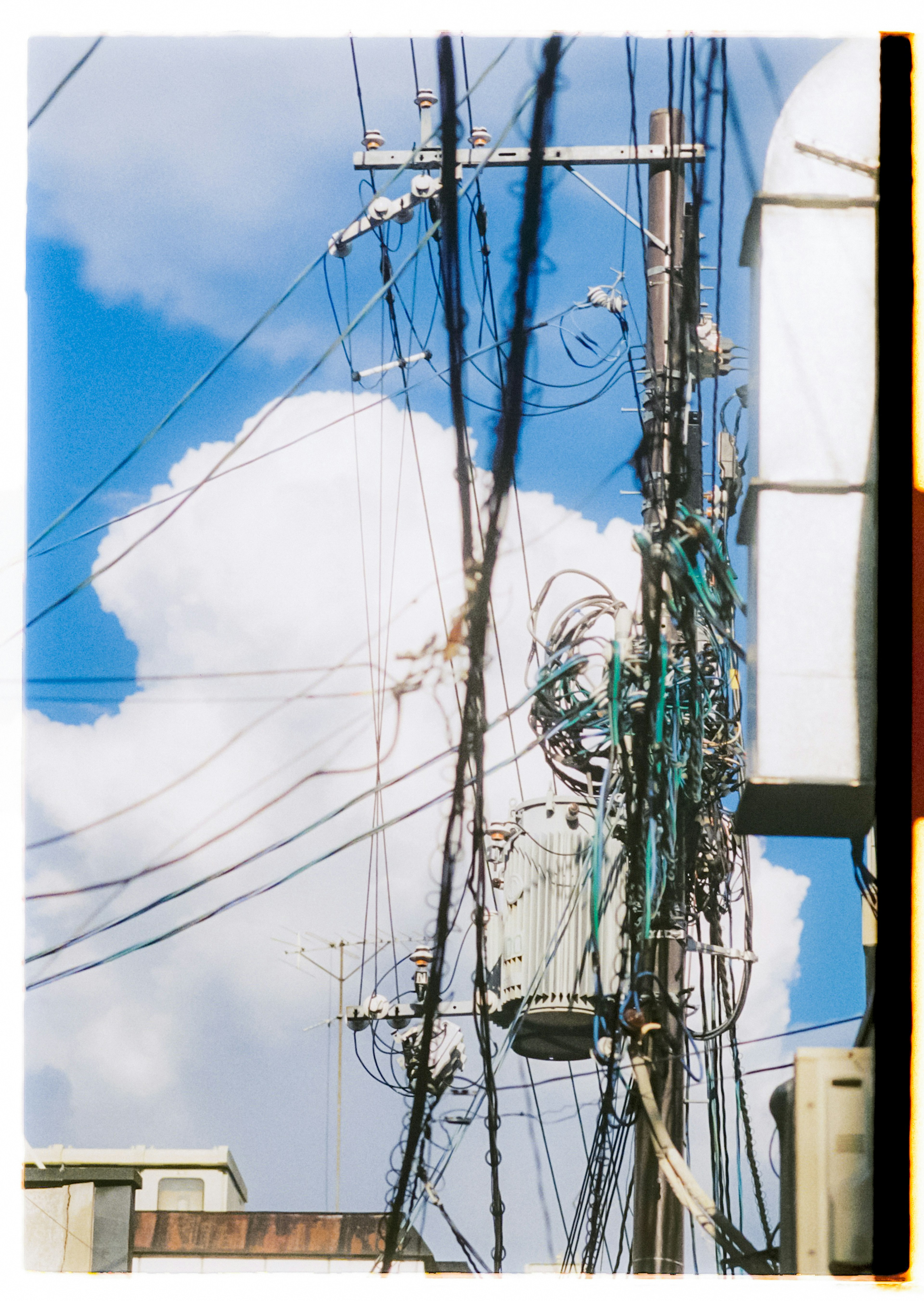 Linee elettriche e pali contro un cielo blu con nuvole bianche