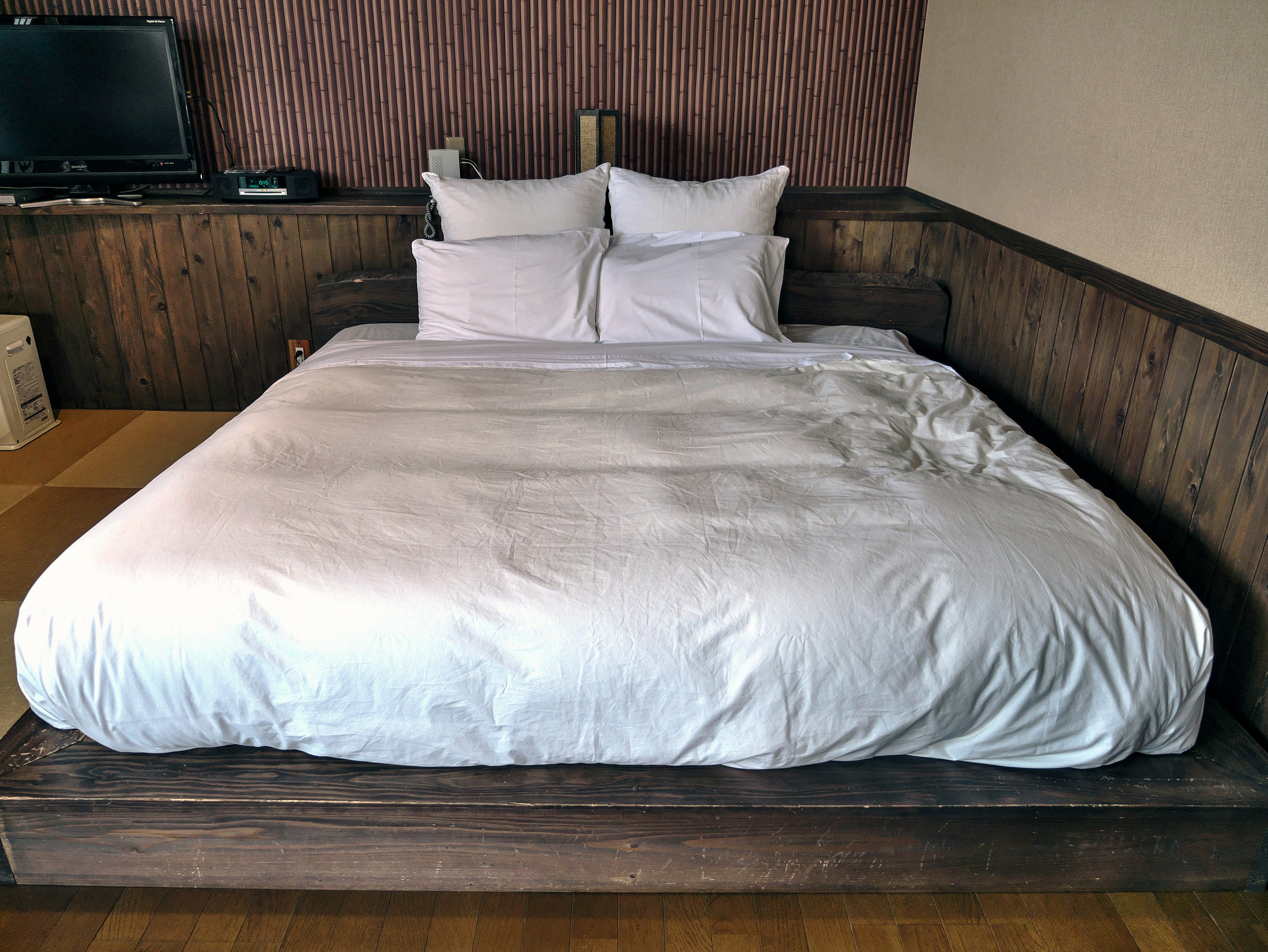 Design de chambre moderne avec une grande couette blanche et des oreillers cadre de lit en bois et mur