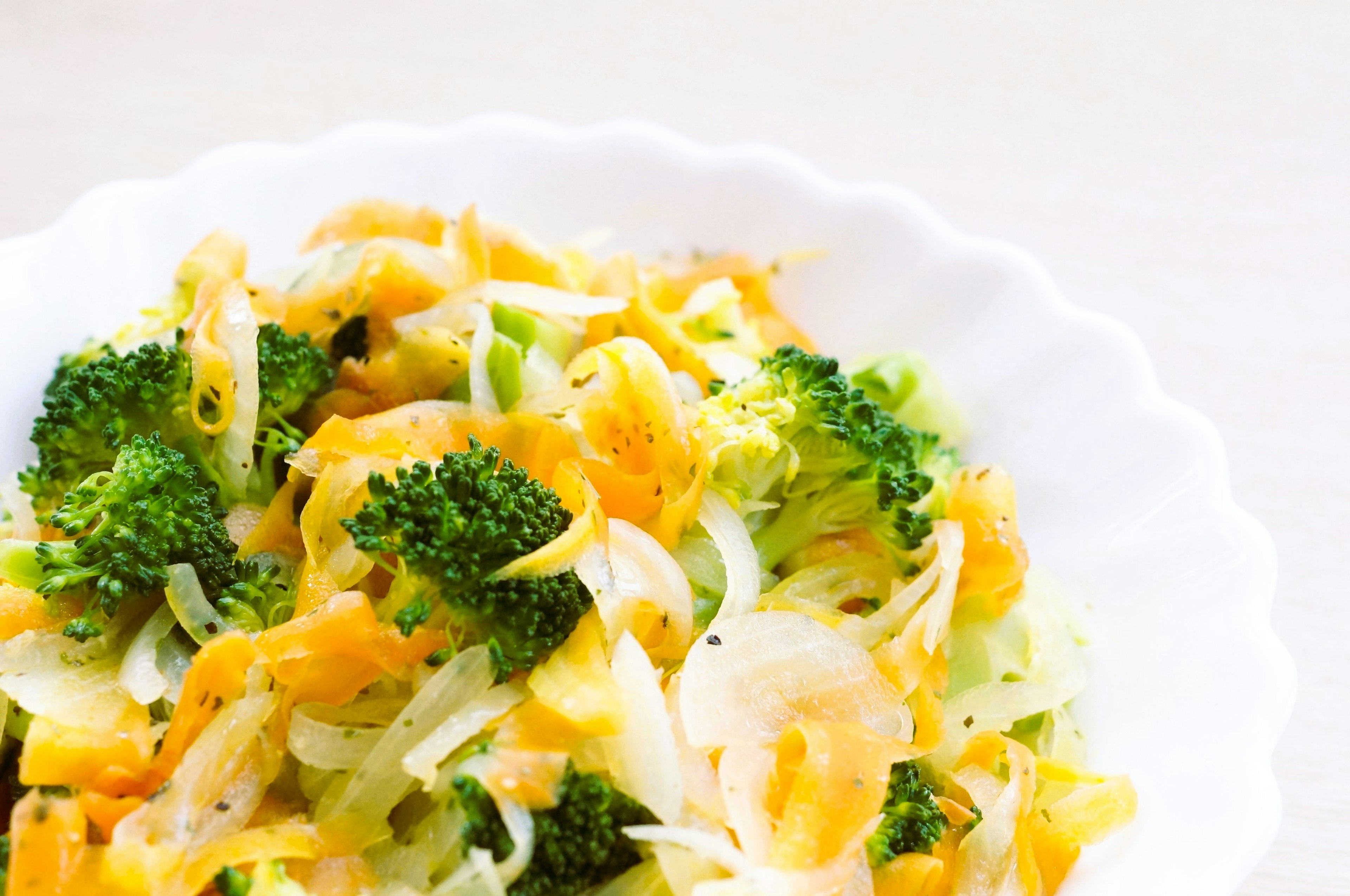 A colorful salad featuring broccoli, cabbage, and shredded carrots in a white bowl