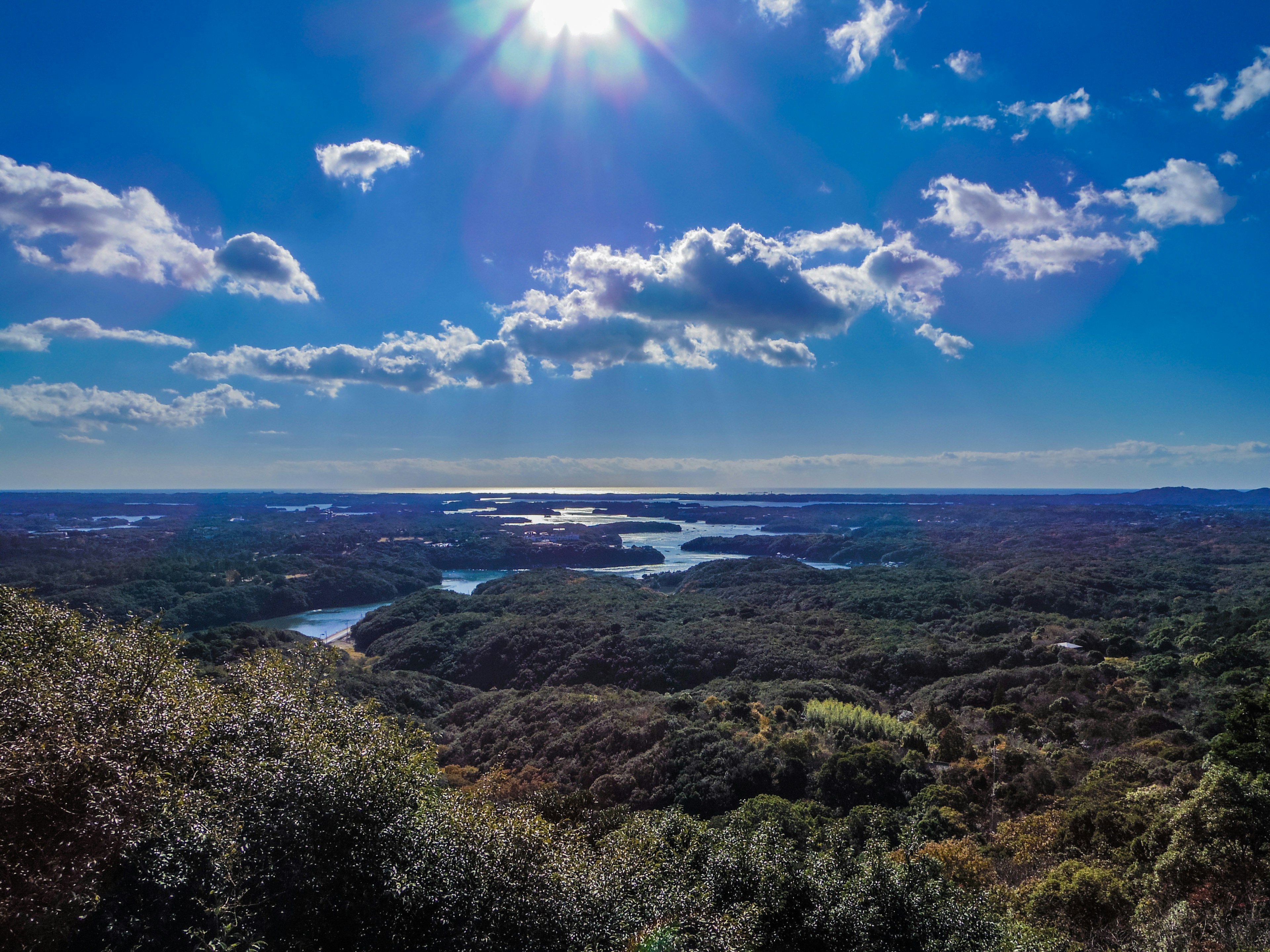 Panoramic view of green hills and lakes under a blue sky