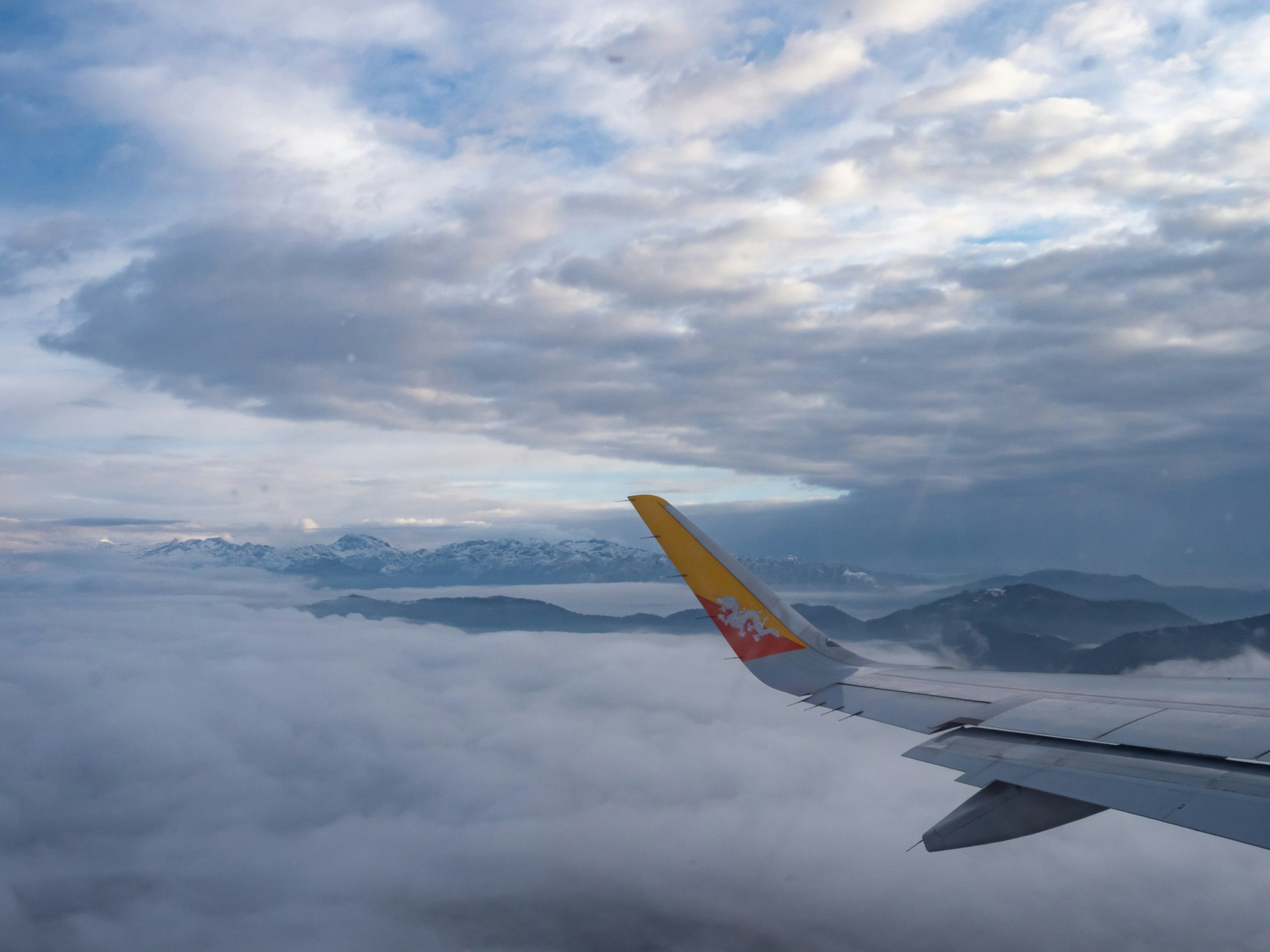 Ala de avión sobre las nubes con cielo azul y nubes blancas