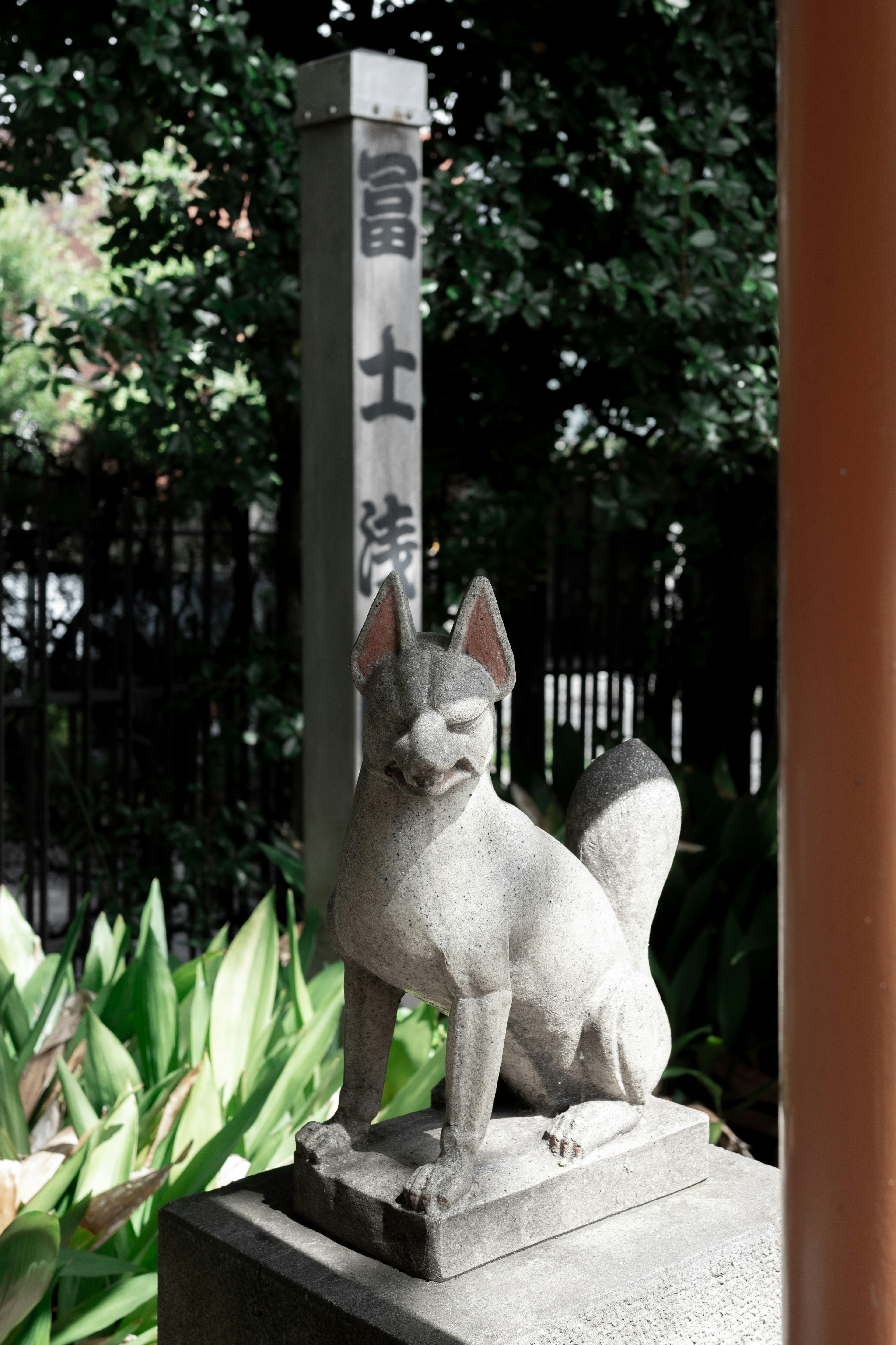 Estatua de zorro de piedra con un letrero japonés al fondo