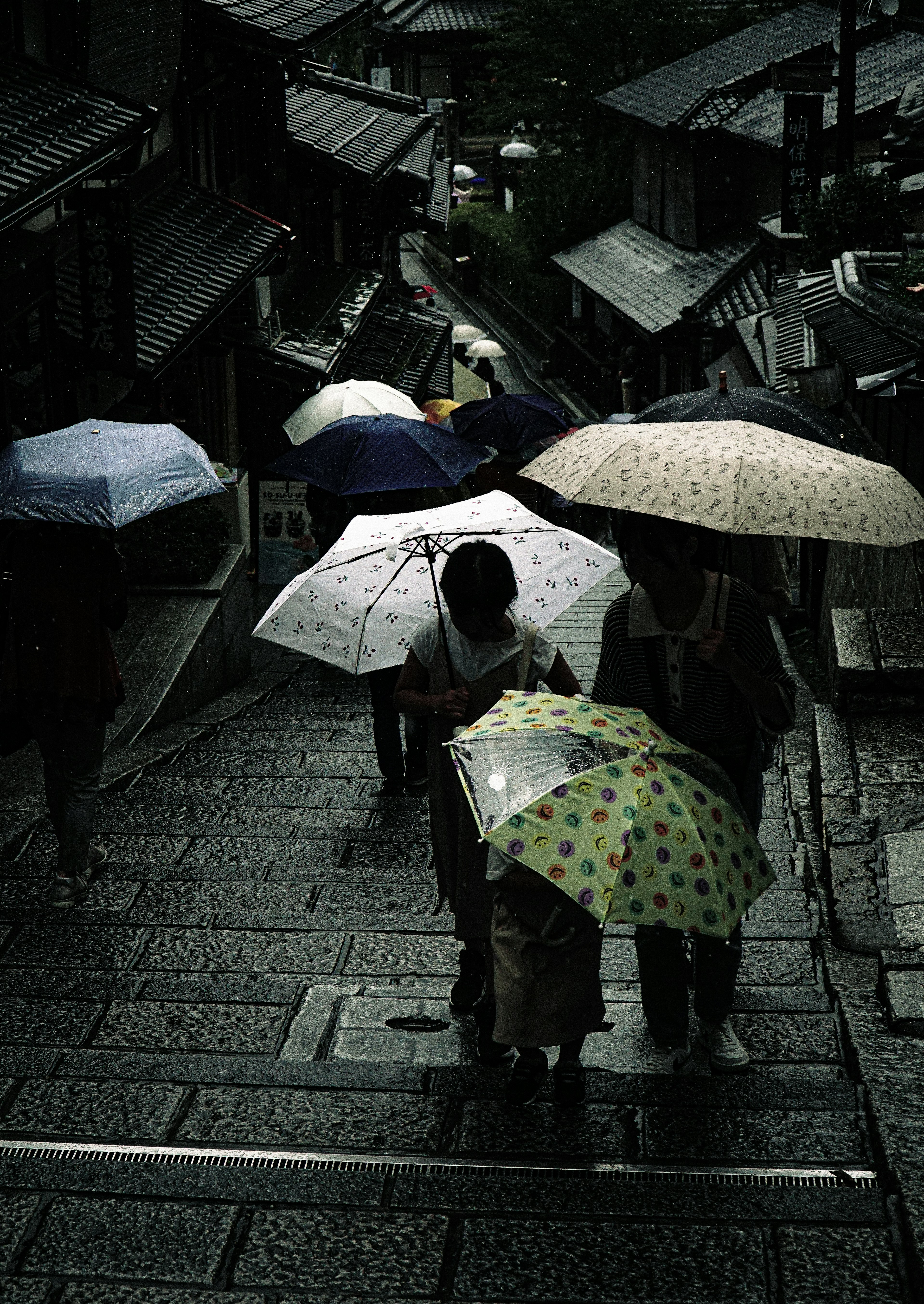 Menschen mit Regenschirmen gehen die Steinstufen in einer regnerischen Umgebung mit einem dunklen grünen Hintergrund hinunter