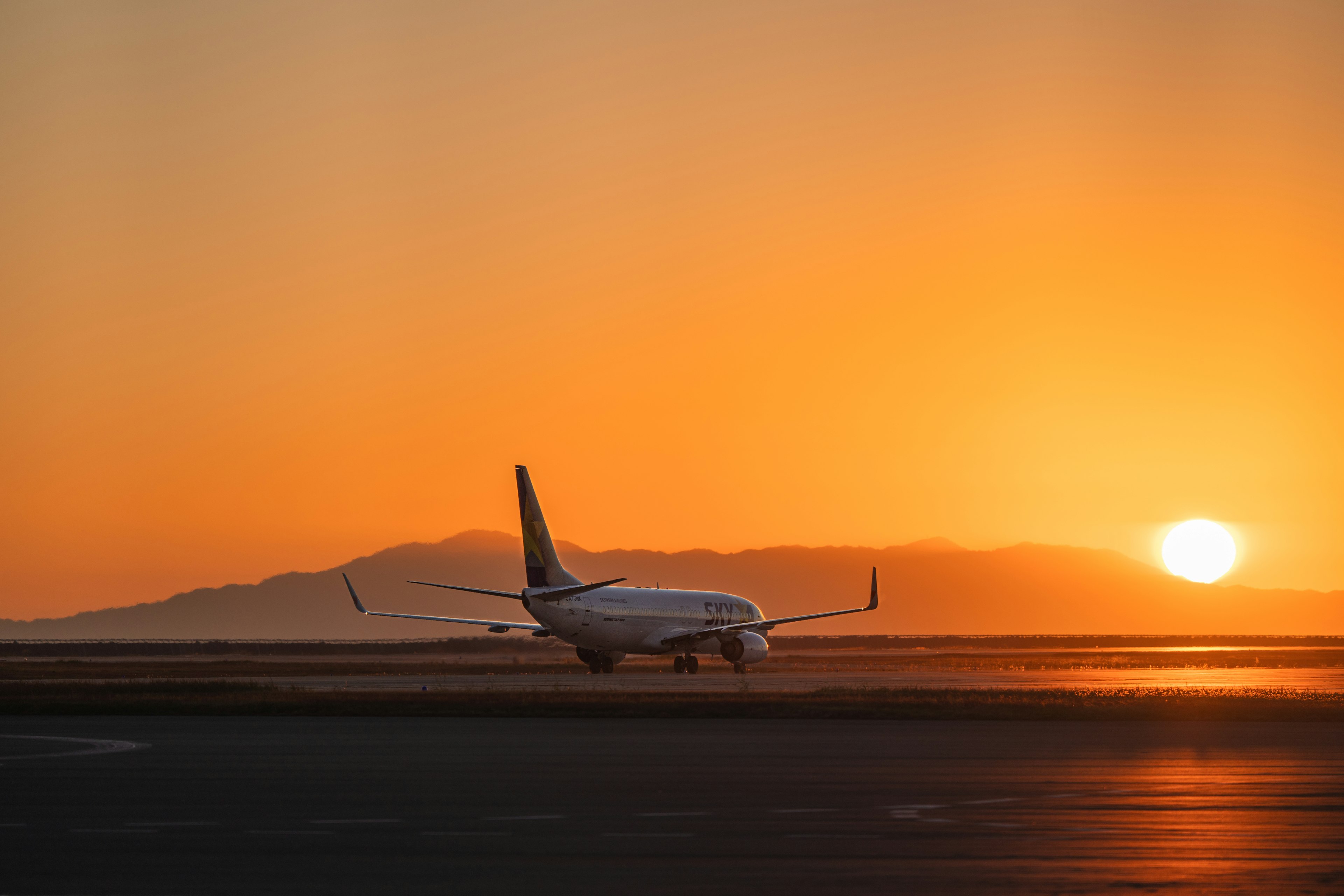 Un avion sur la piste avec un coucher de soleil en arrière-plan