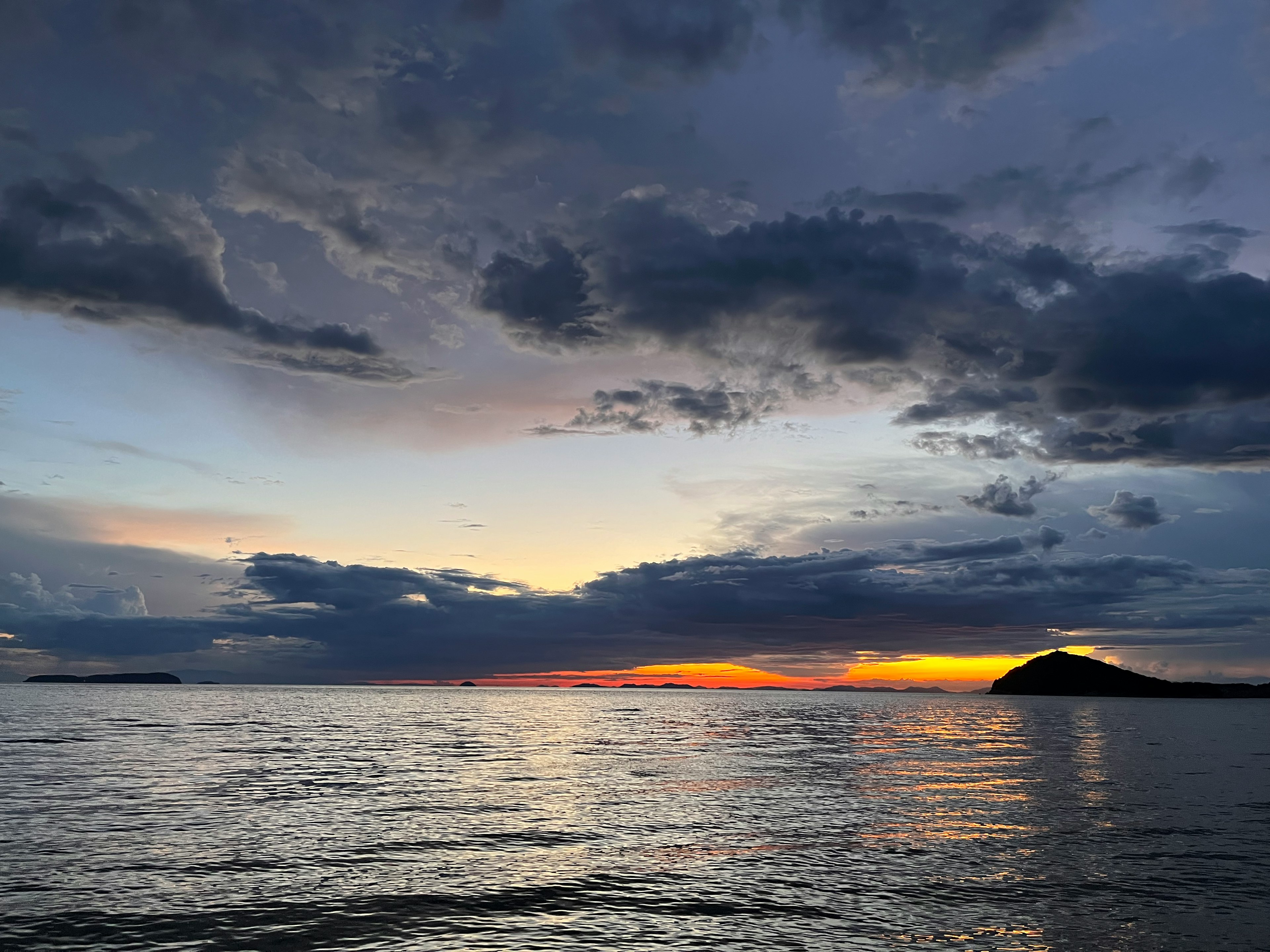 Mer tranquille avec des nuages sombres au coucher du soleil