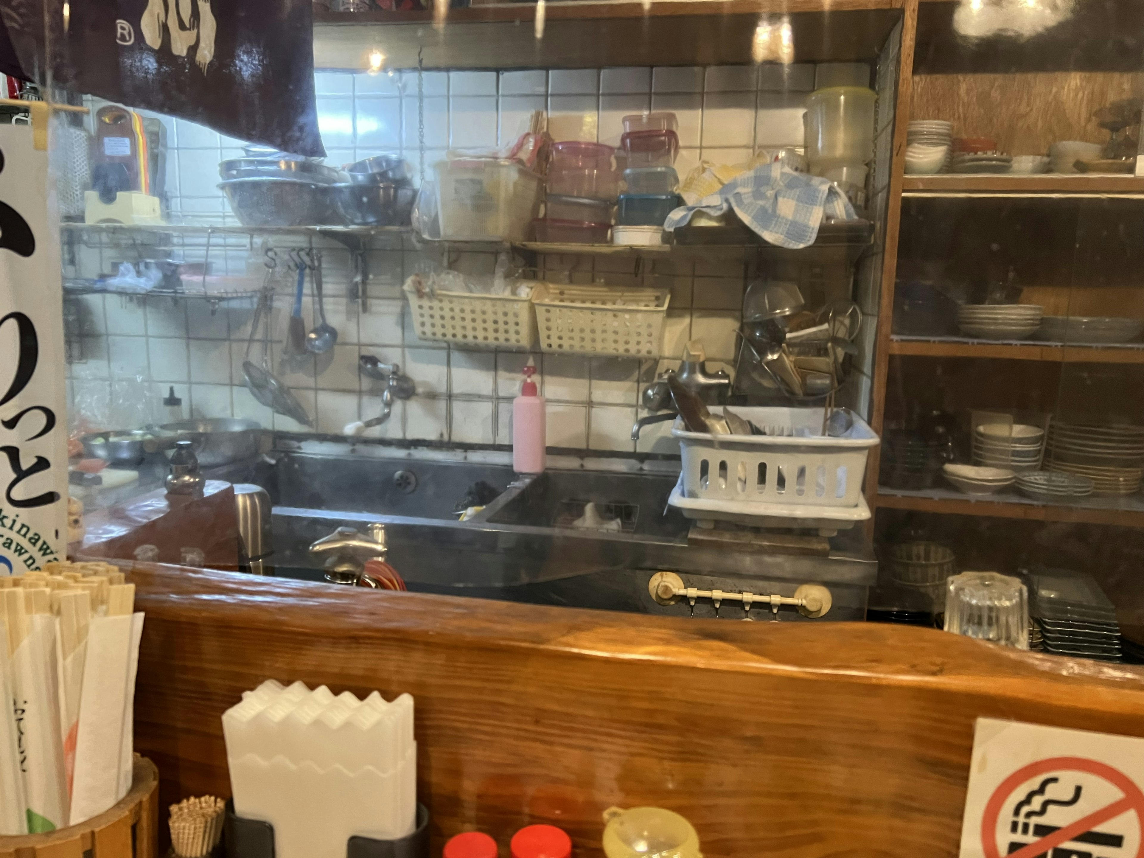 View of a kitchen counter with various utensils and a shelf behind